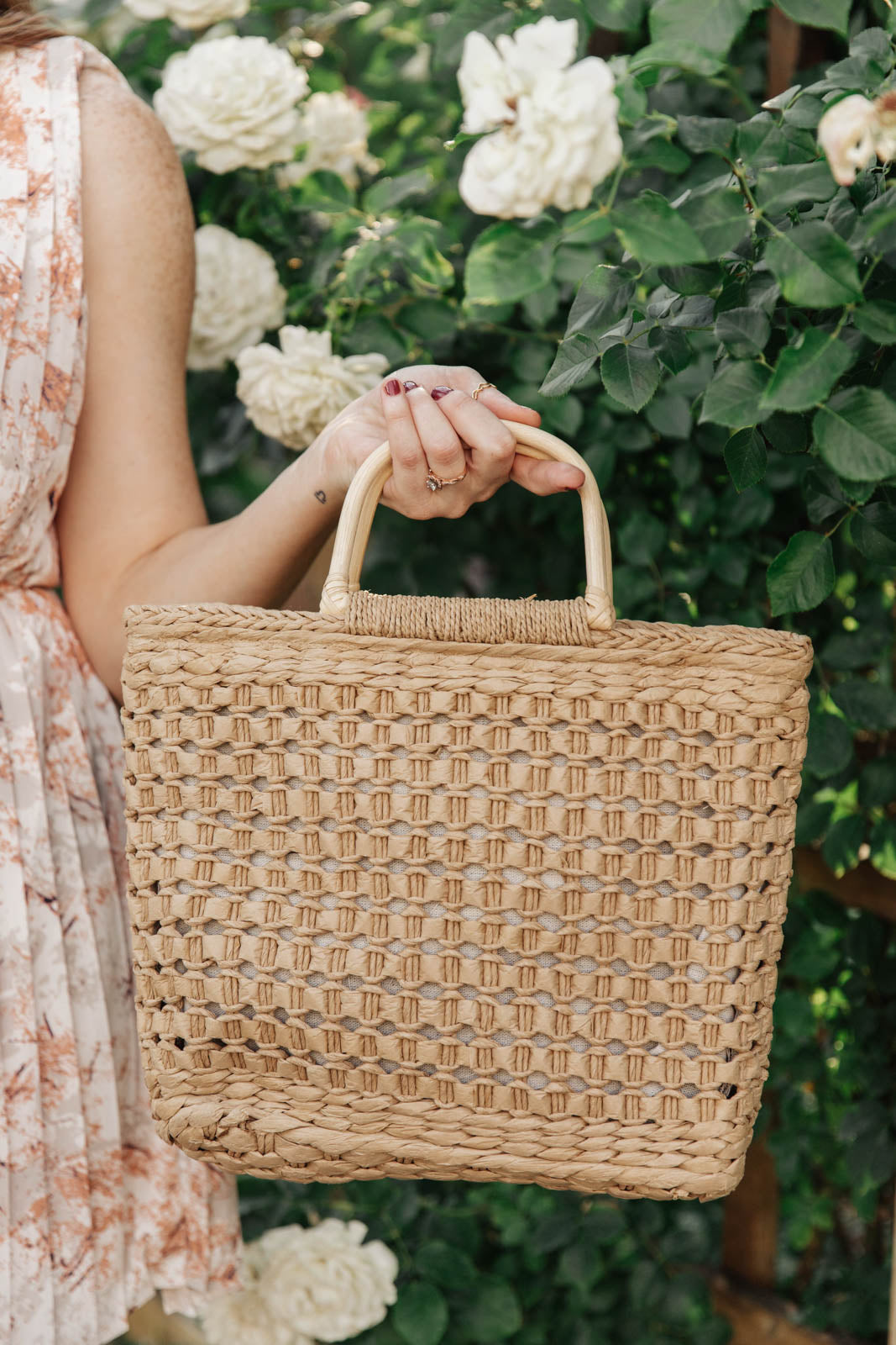 A stylish Mini Market Tote bag with a woven design, wooden handle, and adjustable strap, perfect for beach outings.