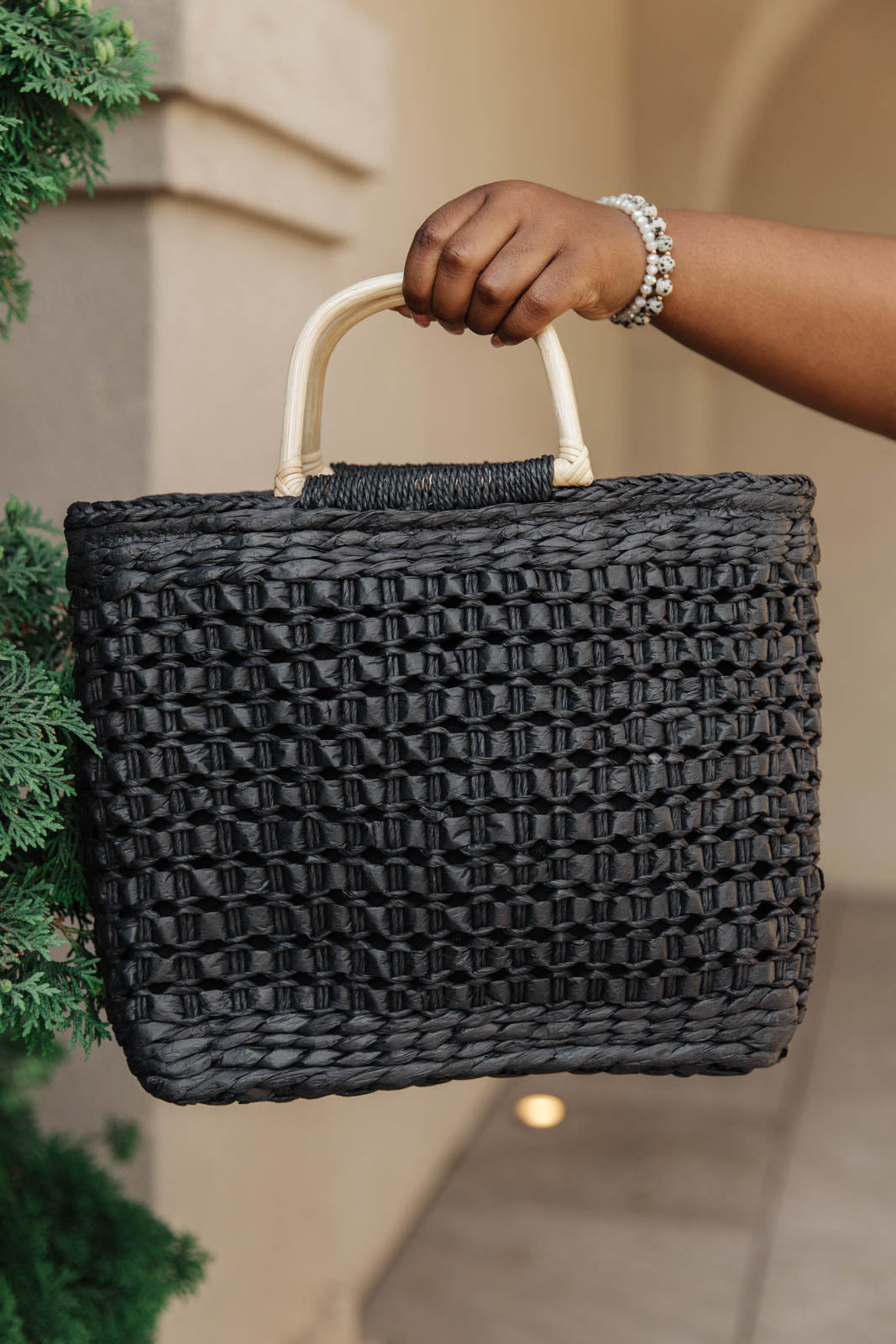 A stylish Mini Market Tote bag with a woven design, wooden handle, and adjustable strap, perfect for beach outings.