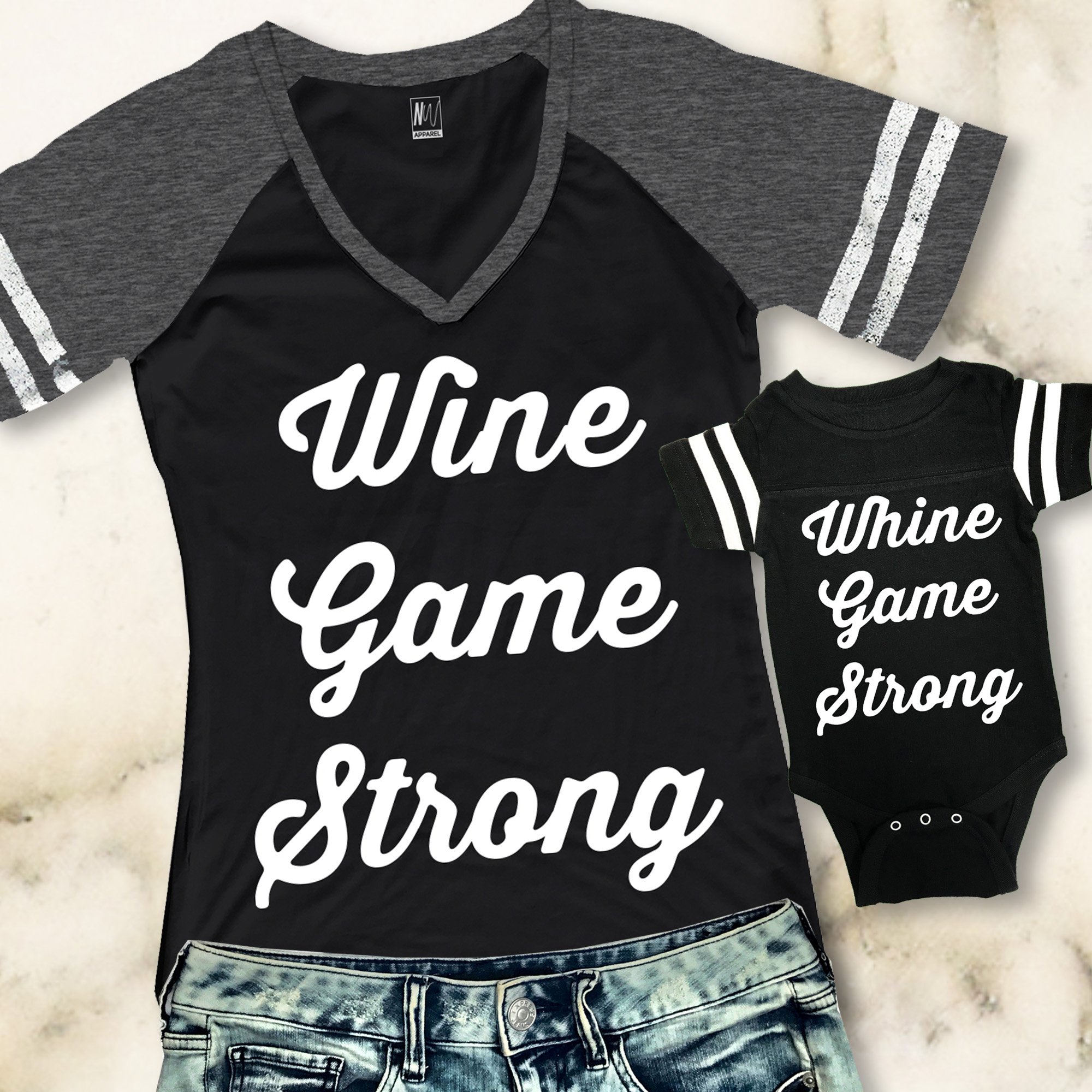 Mom wearing a 'WINE GAME STRONG' V-neck shirt with baby in a 'WHINE GAME STRONG' jumpsuit, showcasing a stylish matching outfit.