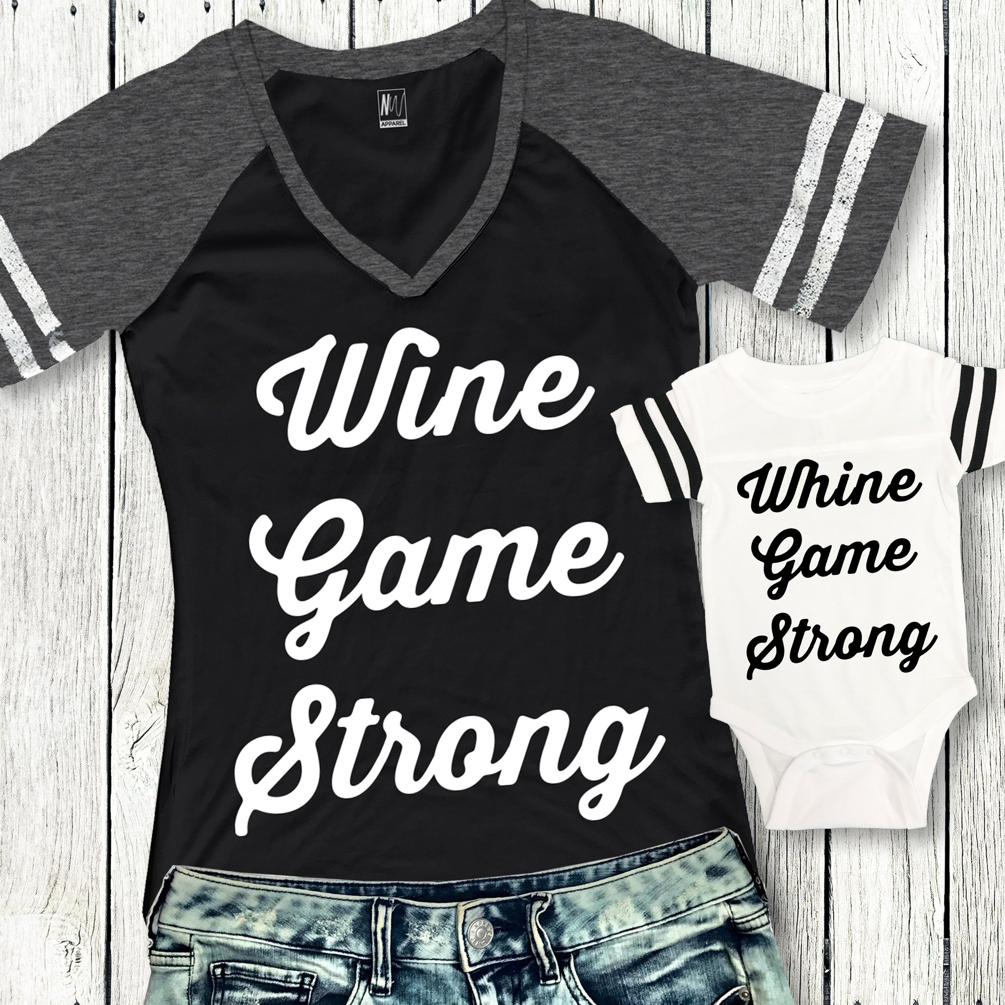 Mom wearing a 'WINE GAME STRONG' V-neck shirt with baby in a 'WHINE GAME STRONG' jumpsuit, showcasing a stylish matching outfit.