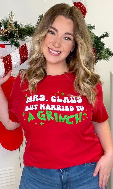 Mrs. Claus But Married to A Grinch Graphic T-Shirt in vibrant red with green sparkles, showcasing a fun Christmas design.