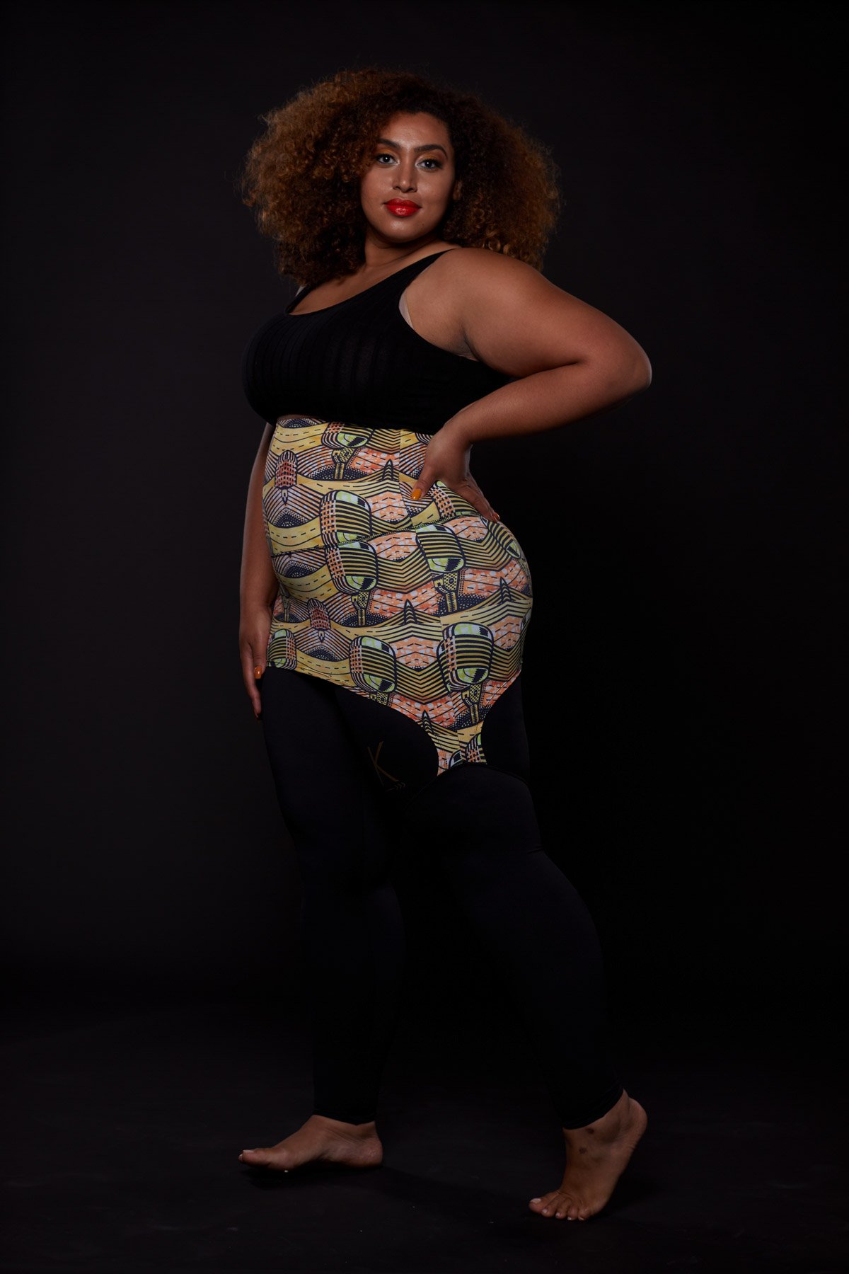 A stylish plus-sized woman wearing the Musical Skirt, showcasing its vibrant African print and comfortable fit during a workout.