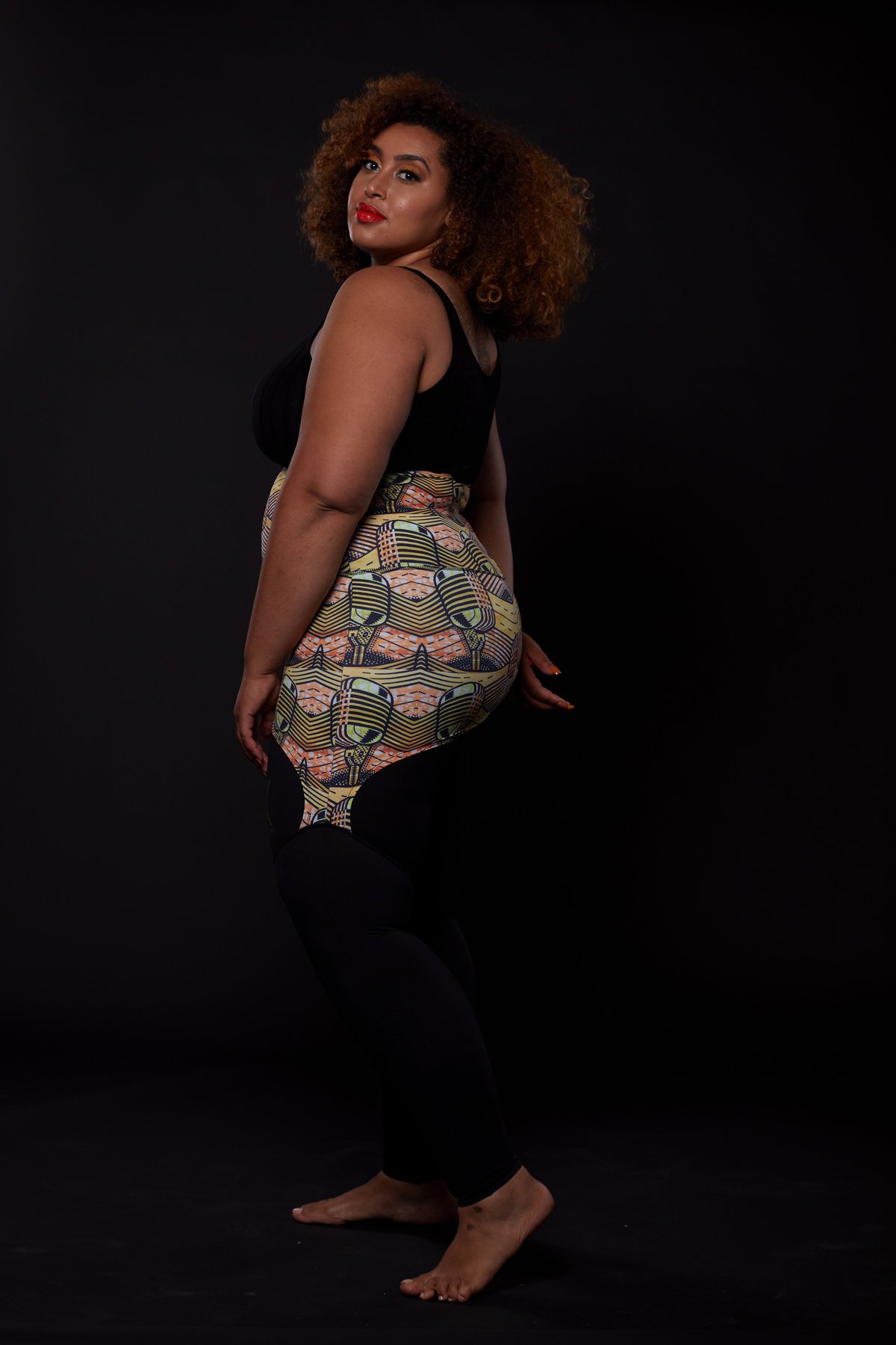 A stylish plus-sized woman wearing the Musical Skirt, showcasing its vibrant African print and comfortable fit during a workout.