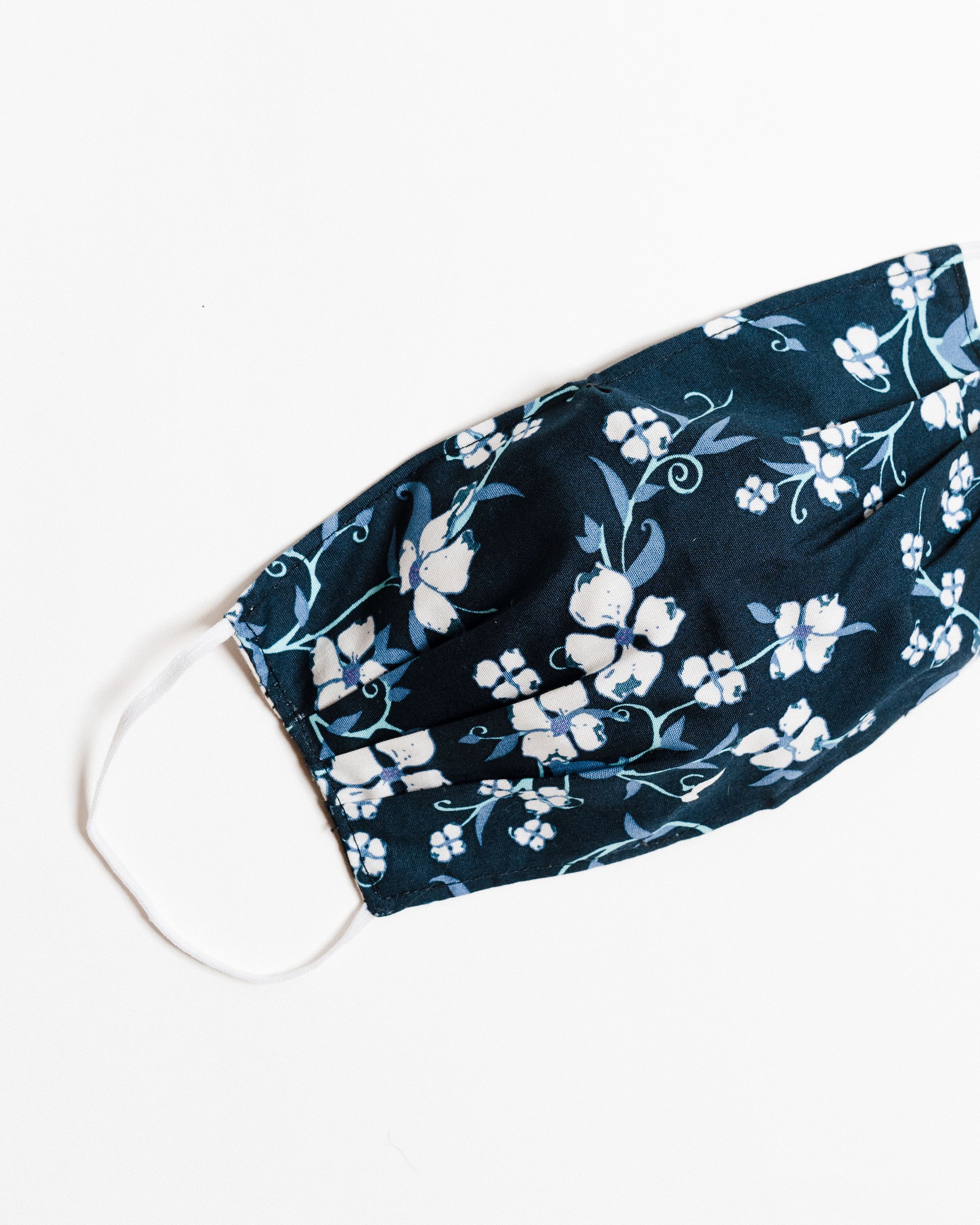 Navy floral face mask made of breathable cotton with elastic ear straps, featuring a stylish floral design.