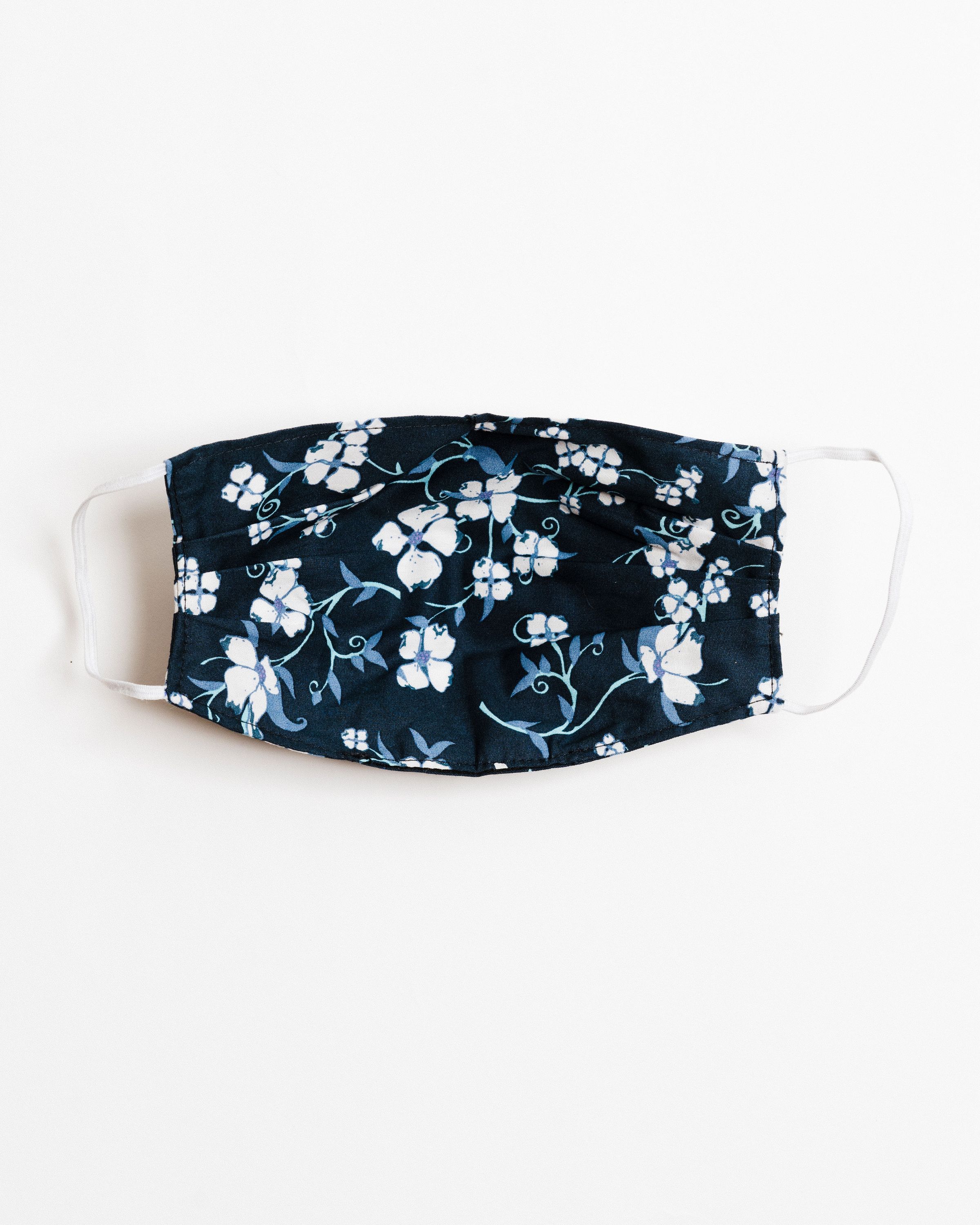 Navy floral face mask made of breathable cotton with elastic ear straps, featuring a stylish floral design.