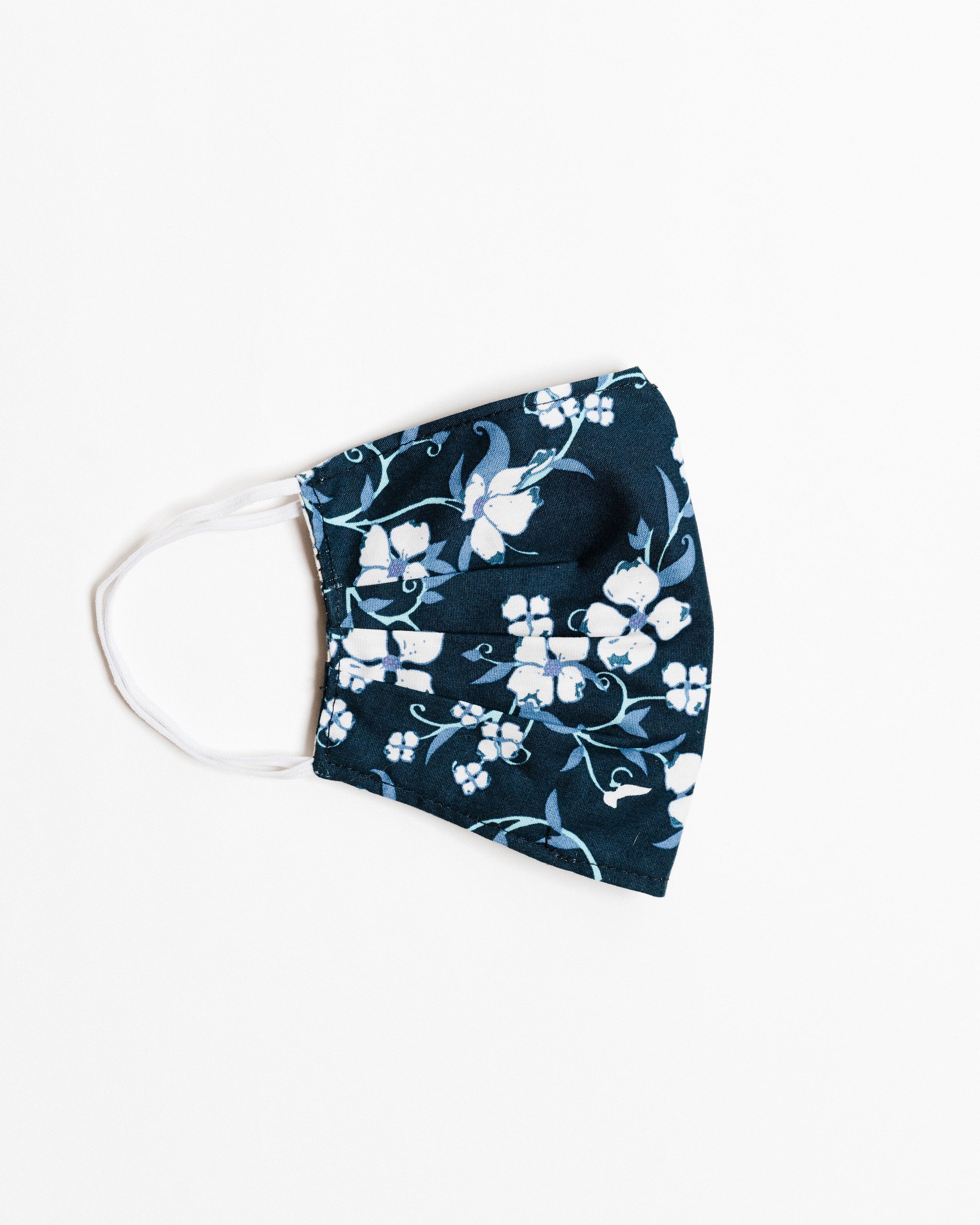 Navy floral face mask made of breathable cotton with elastic ear straps, featuring a stylish floral design.