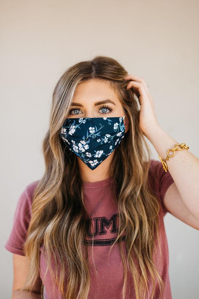 Navy floral face mask made of breathable cotton with elastic ear straps, featuring a stylish floral design.