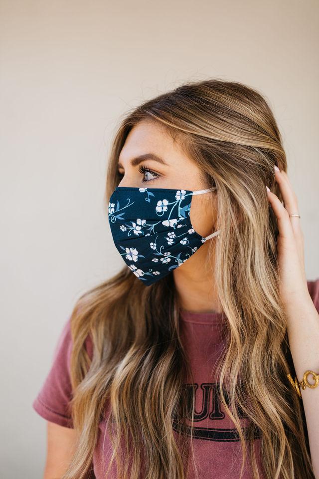 Navy floral face mask made of breathable cotton with elastic ear straps, featuring a stylish floral design.