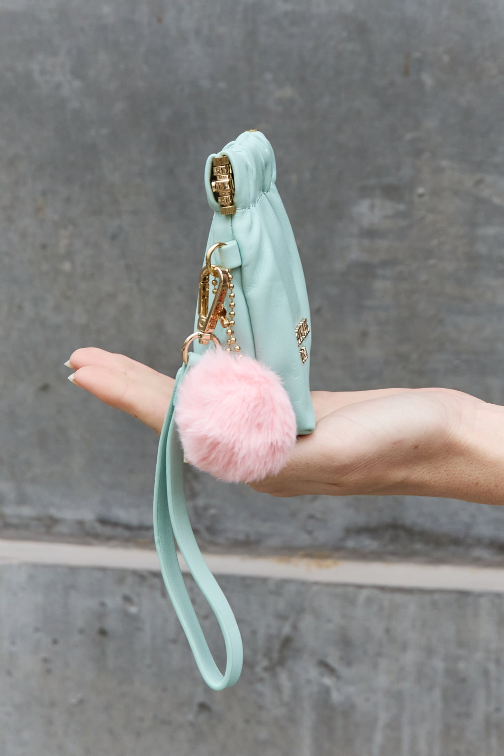 Nicole Lee USA Faux Leather Pouch in two-tone design with gold-tone hardware and detachable pompom keychain.