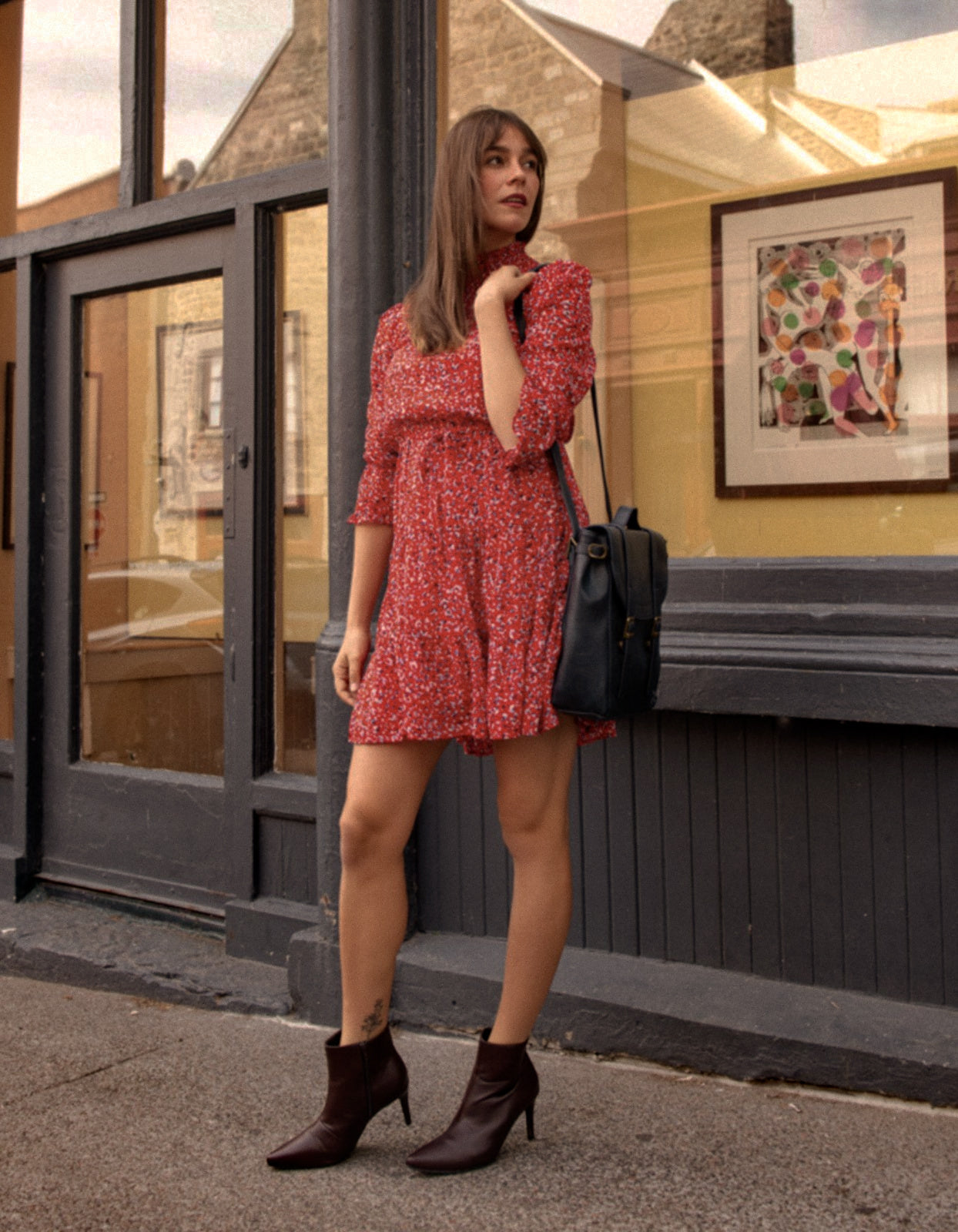 The Noemie Dress featuring a vibrant red print, high neckline, and semi-sheer 3/4 sleeves, perfect for casual chic outings.