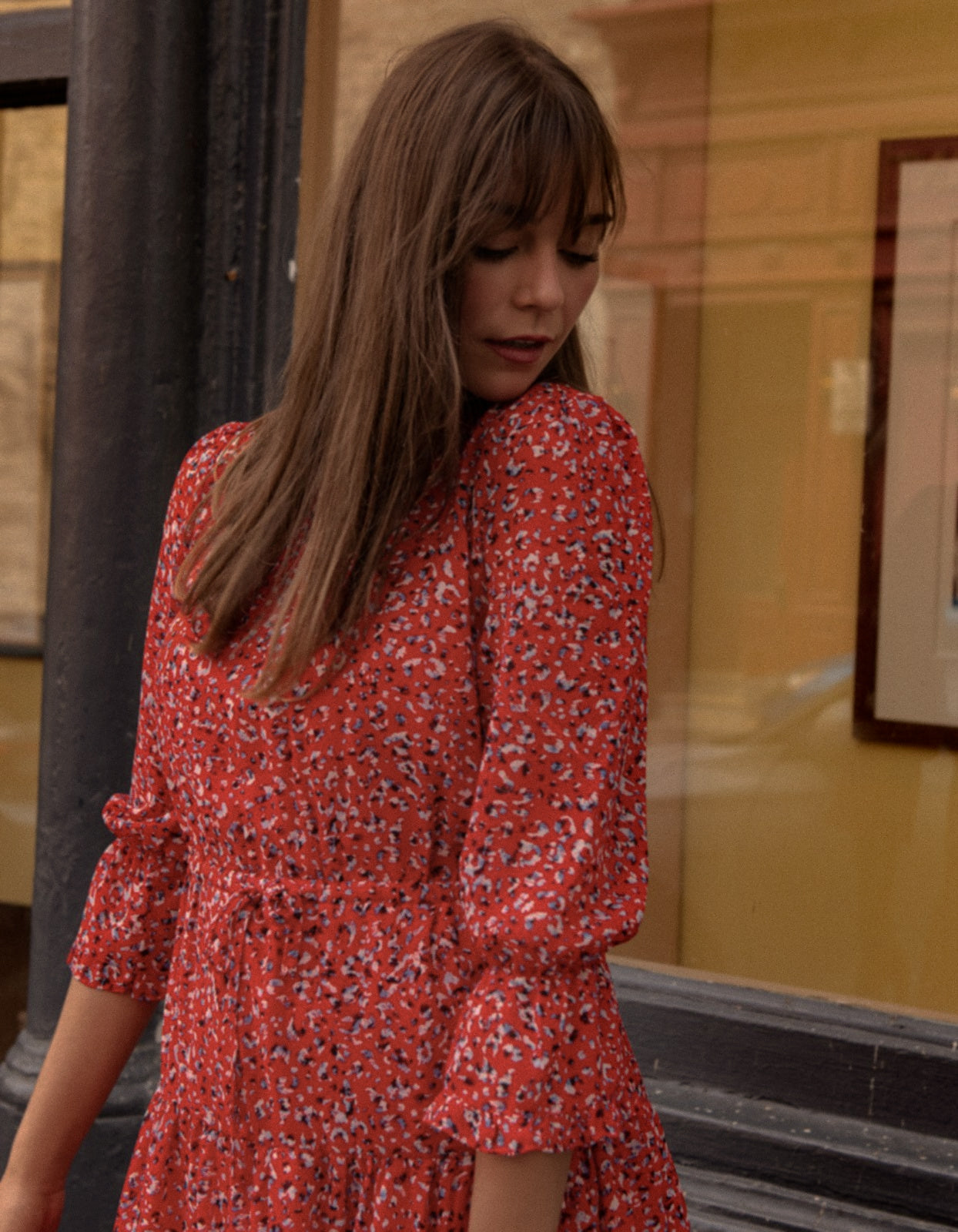 The Noemie Dress featuring a vibrant red print, high neckline, and semi-sheer 3/4 sleeves, perfect for casual chic outings.