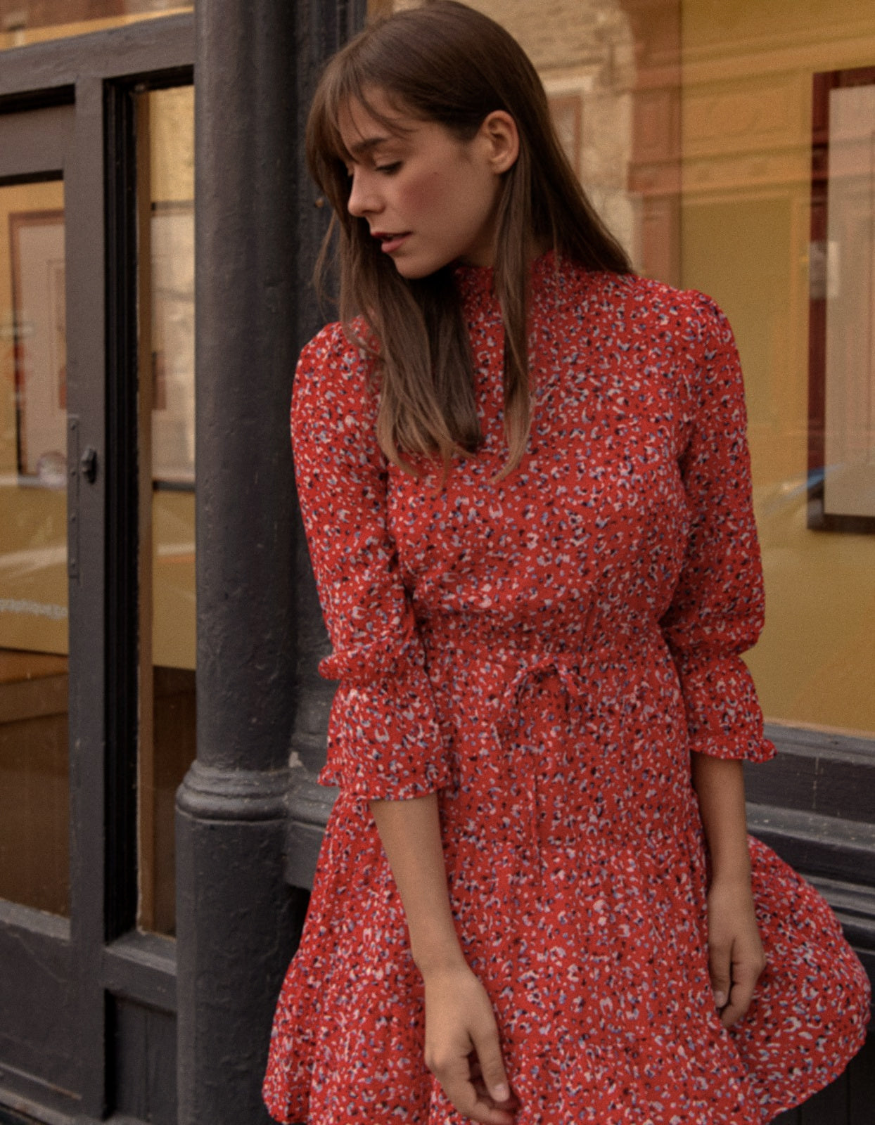 The Noemie Dress featuring a vibrant red print, high neckline, and semi-sheer 3/4 sleeves, perfect for casual chic outings.