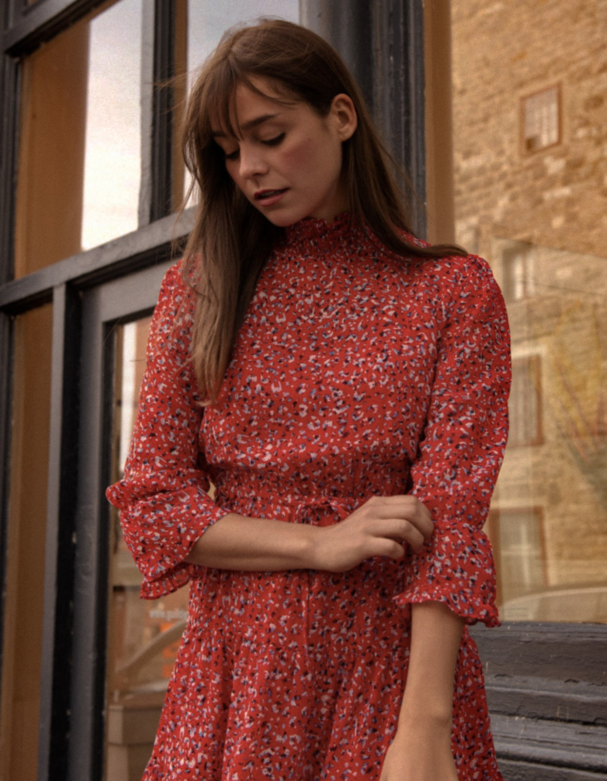 The Noemie Dress featuring a vibrant red print, high neckline, and semi-sheer 3/4 sleeves, perfect for casual chic outings.