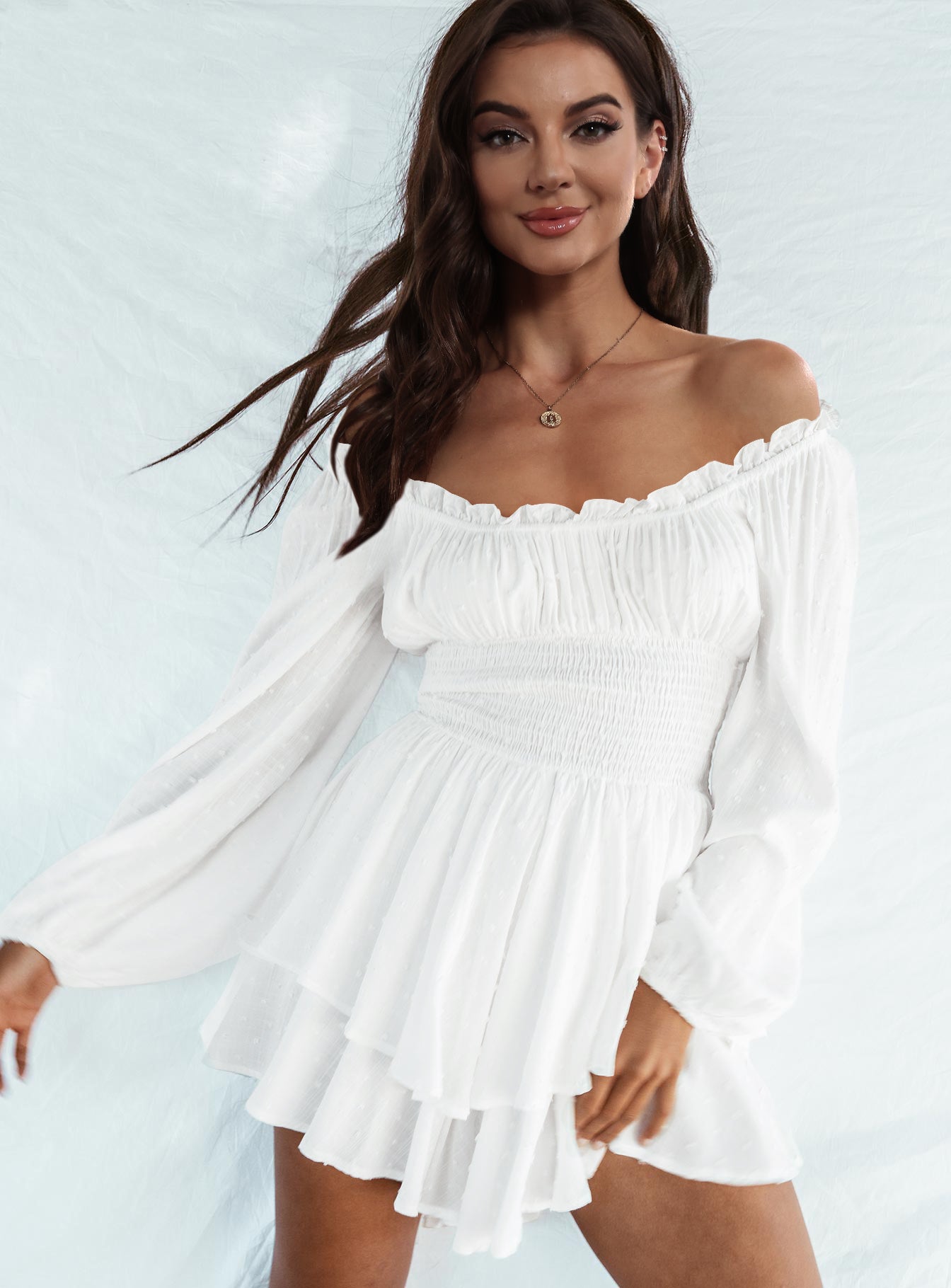 A stylish off-shoulder mini dress with a smocked waist and layered hem, featuring long sleeves and a solid pattern, perfect for casual outings.