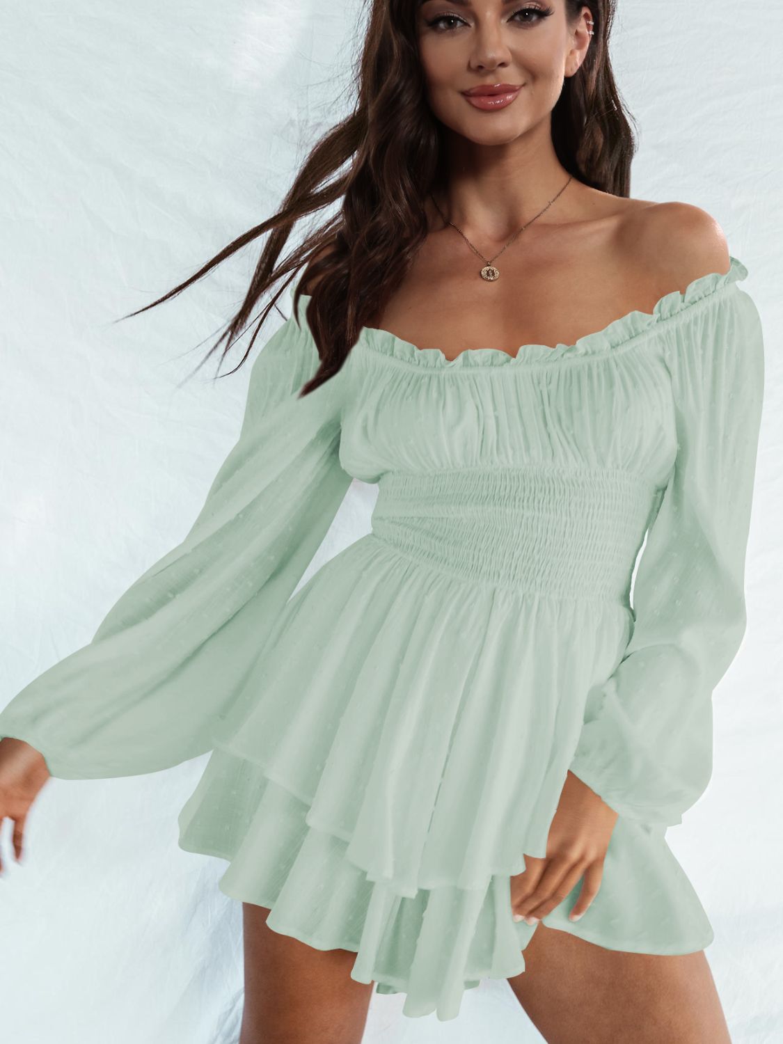 A stylish off-shoulder mini dress with a smocked waist and layered hem, featuring long sleeves and a solid pattern, perfect for casual outings.