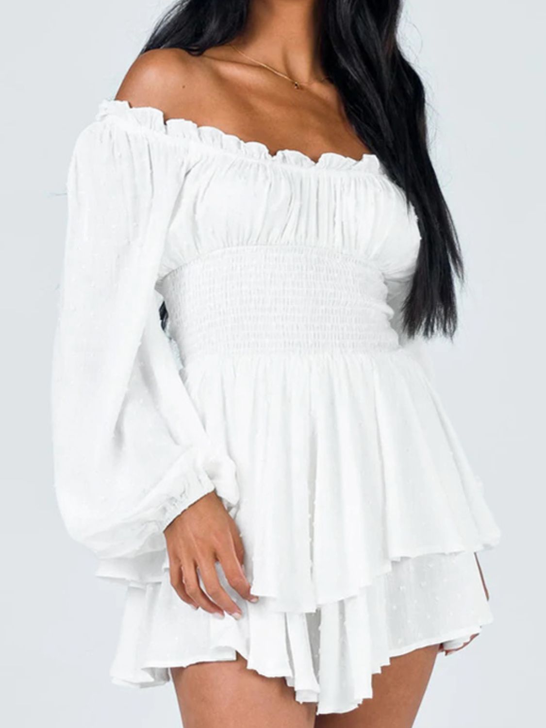 A stylish off-shoulder mini dress with a smocked waist and layered hem, featuring long sleeves and a solid pattern, perfect for casual outings.