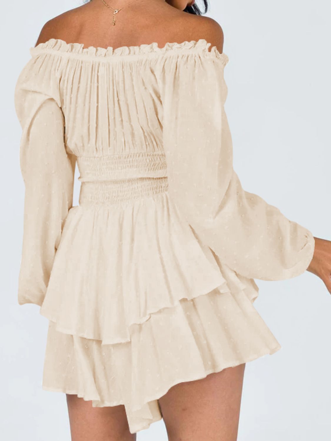 A stylish off-shoulder mini dress with a smocked waist and layered hem, featuring long sleeves and a solid pattern, perfect for casual outings.