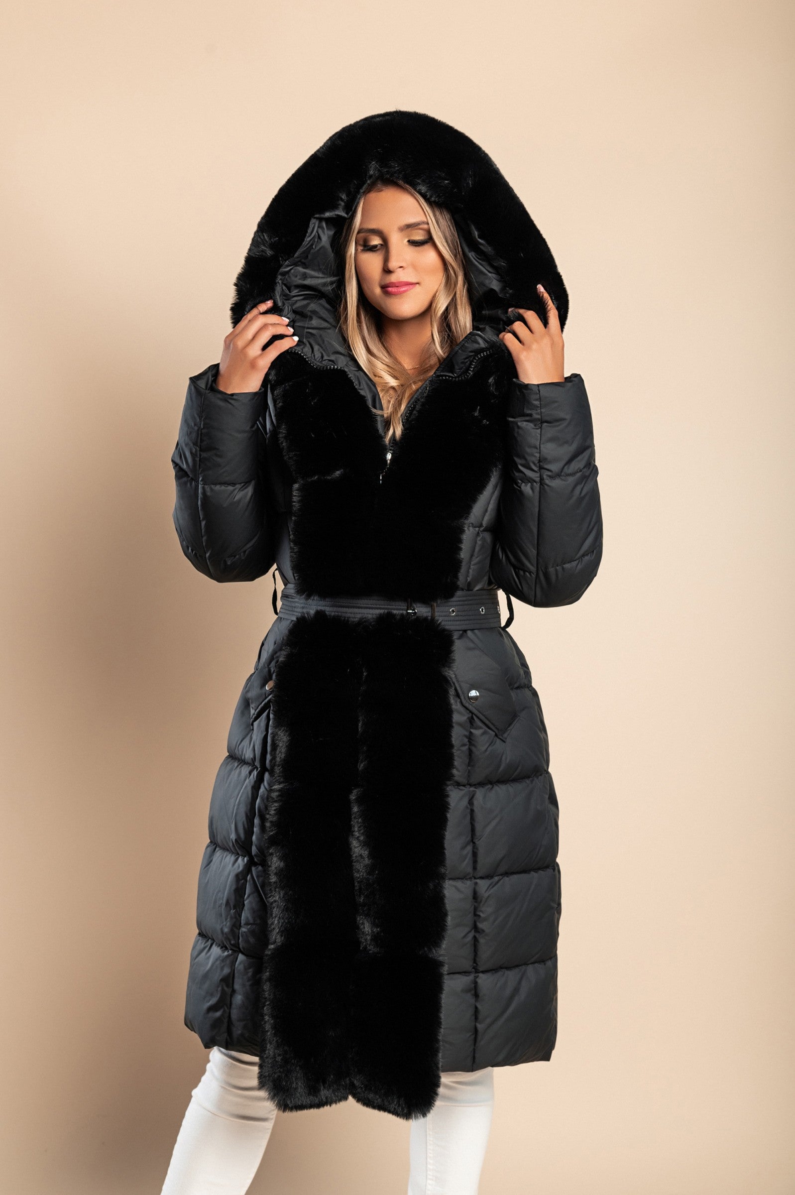 Padded black winter jacket with removable faux fur hood and decorative belt, featuring side pockets and long sleeves.