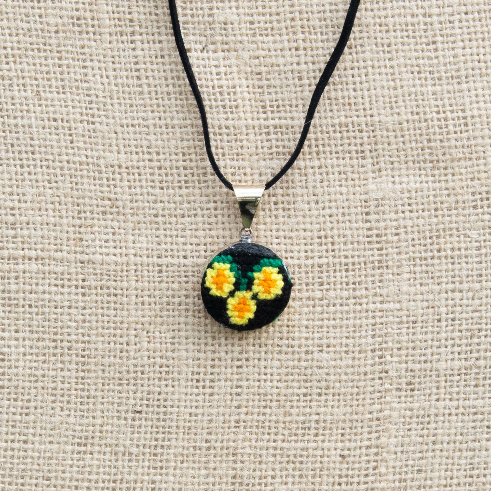 Hand embroidered circular pendant featuring vibrant yellow daisies, showcasing unique craftsmanship from Chiapas, Mexico.