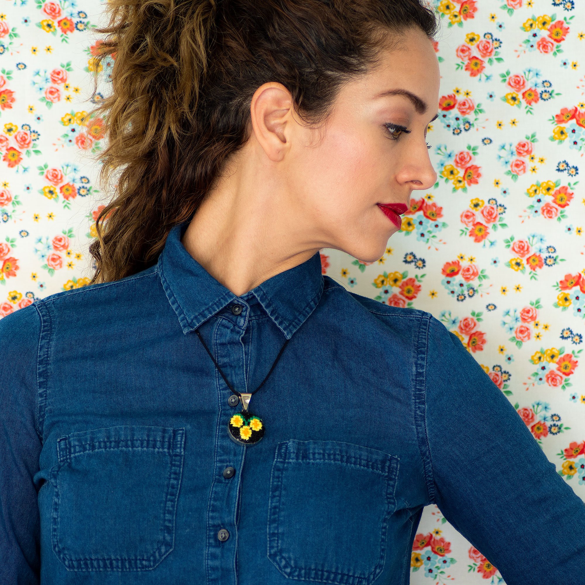 Hand embroidered circular pendant featuring vibrant yellow daisies, showcasing unique craftsmanship from Chiapas, Mexico.