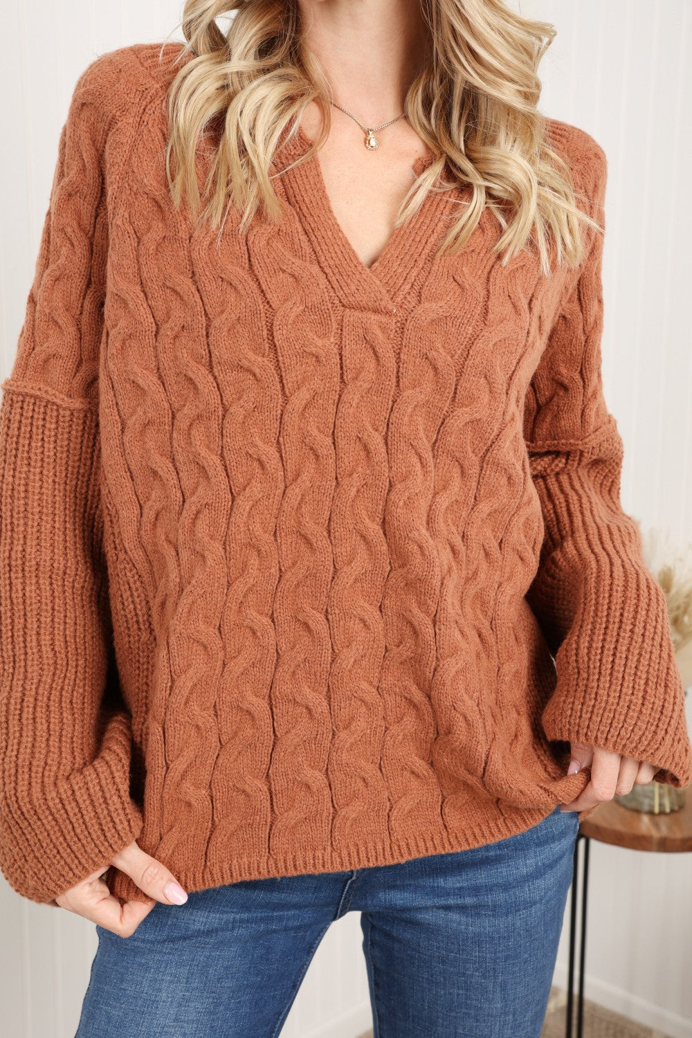 Petal Dew Cable-Knit Notched Sweater featuring a ribbed design, notched neckline, and dropped shoulders in a stylish studio setting.