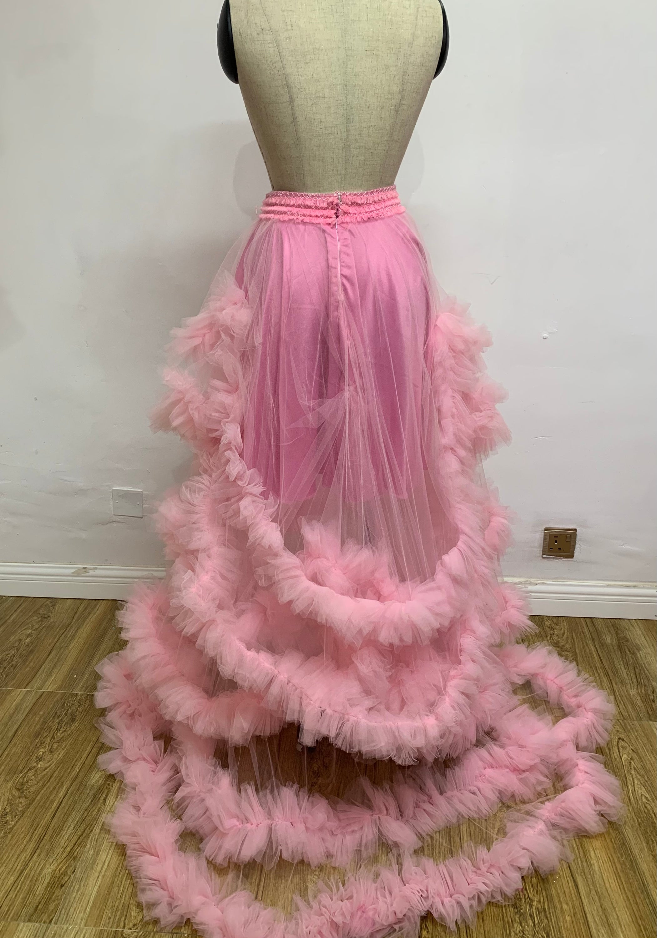 A beautiful floor-length Pink Candice Skirt made of airy tulle, featuring a tiered design and soft pink hue, perfect for romantic occasions.