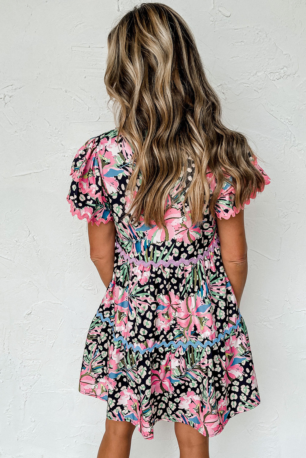 A stylish pink floral mini dress with ricrac embellishments, featuring a tiered design and short sleeves, perfect for casual outings.