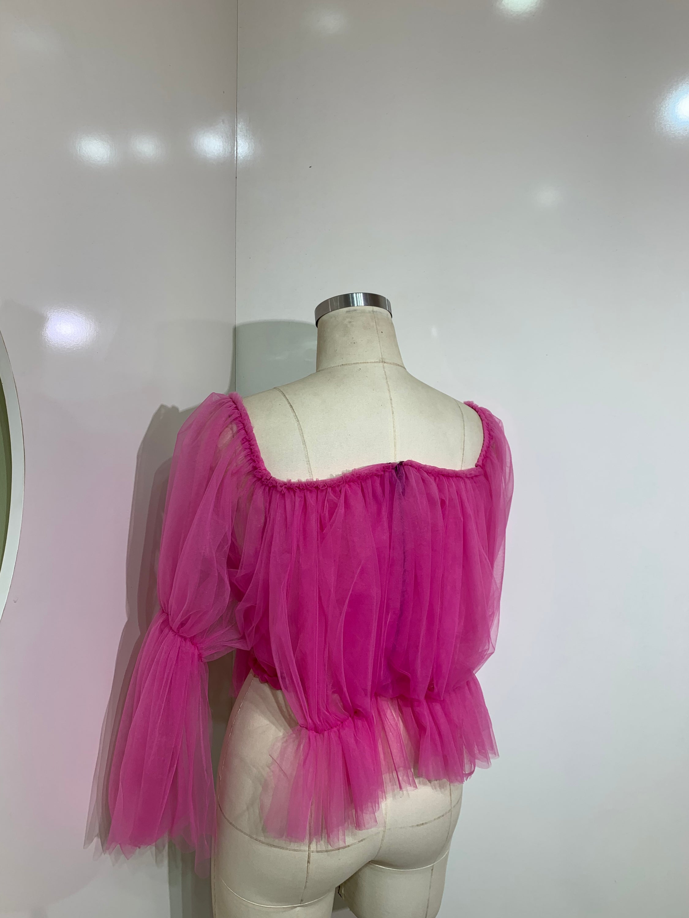 A stylish pink off-shoulder top made of delicate tulle fabric, showcasing a feminine design perfect for various occasions.