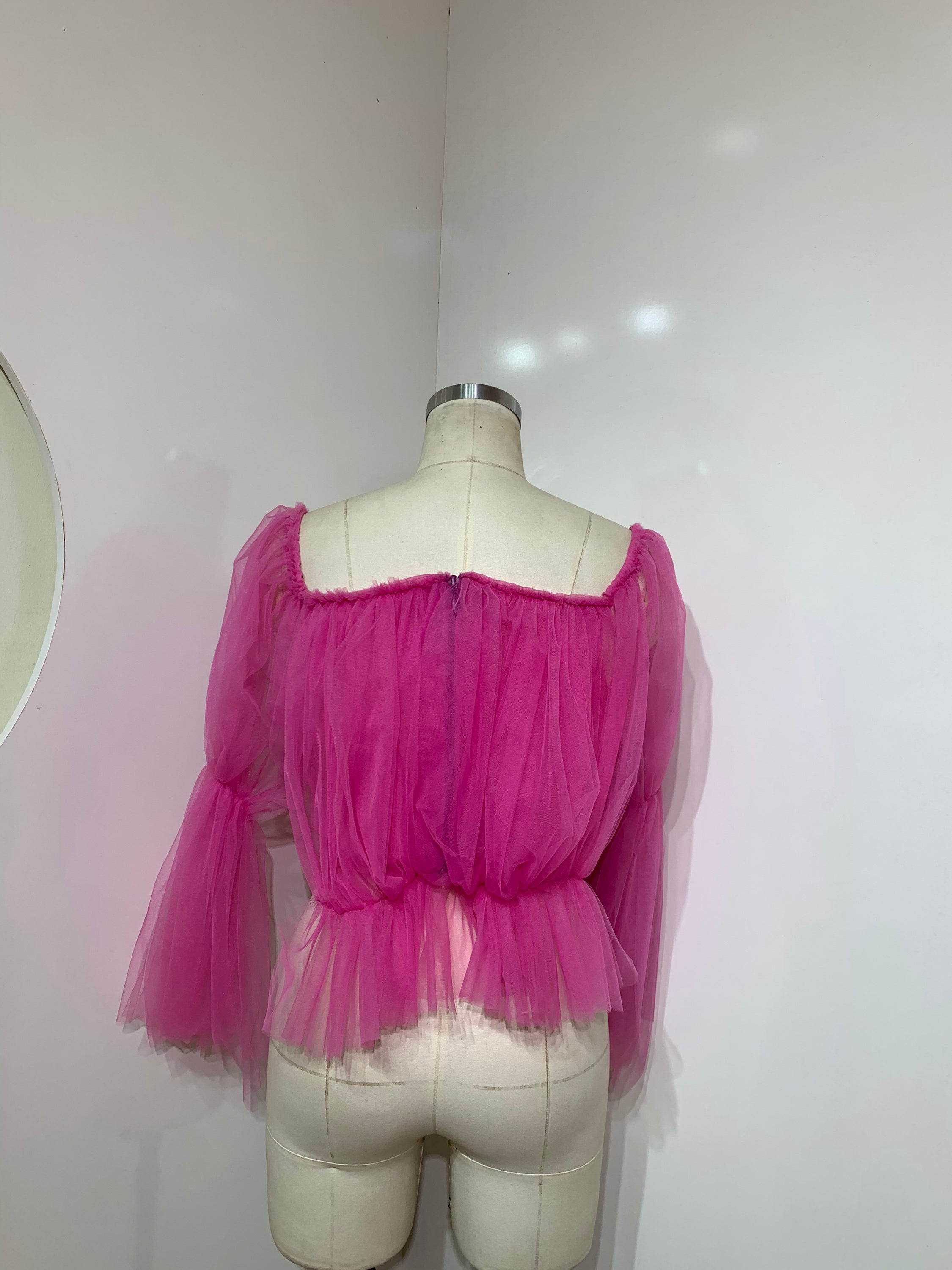 A stylish pink off-shoulder top made of delicate tulle fabric, showcasing a feminine design perfect for various occasions.