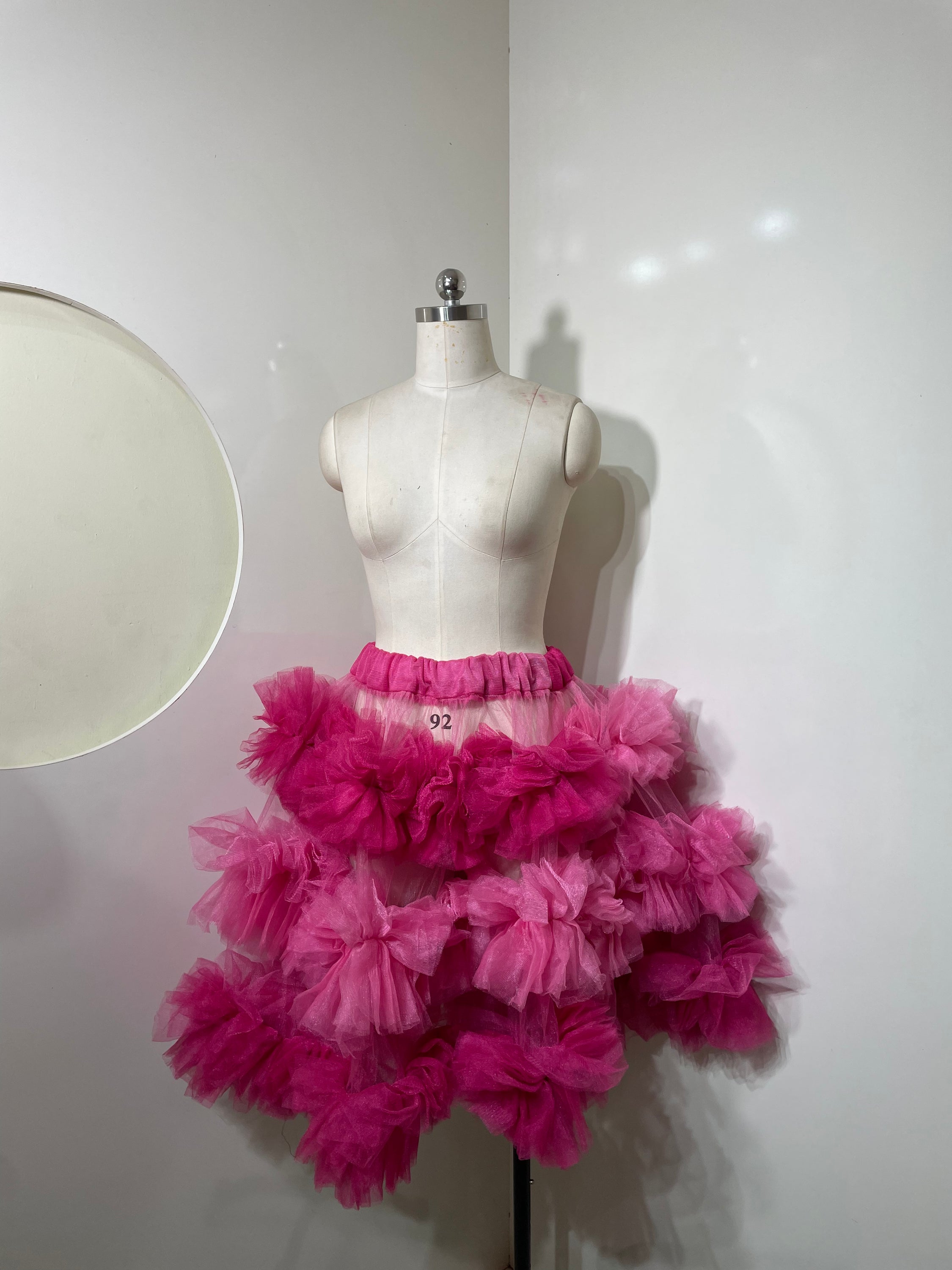 A vibrant pink tiered skirt with ruffle detailing, showcasing a playful and elegant silhouette.