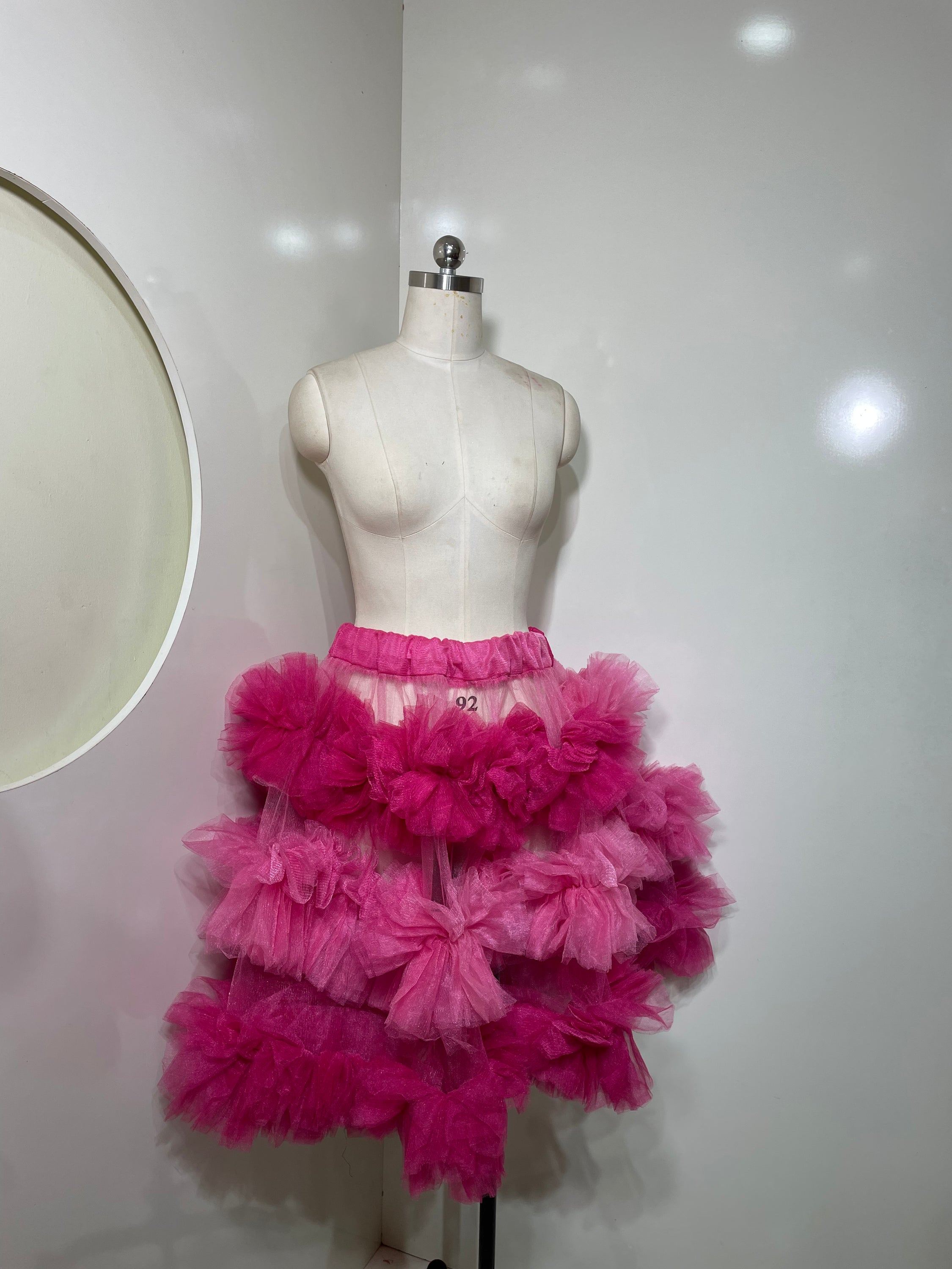 A vibrant pink tiered skirt with ruffle detailing, showcasing a playful and elegant silhouette.