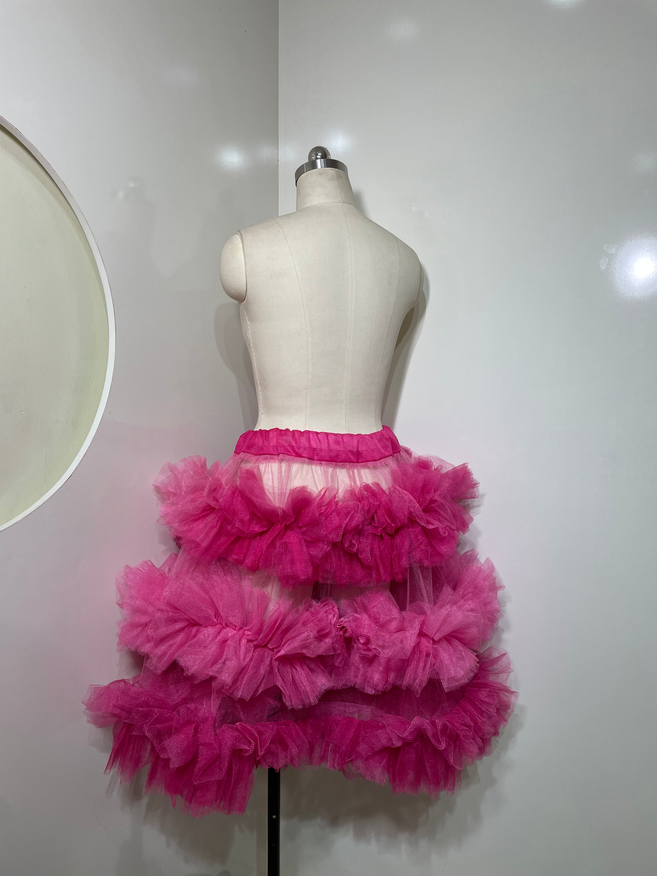 A vibrant pink tiered skirt with ruffle detailing, showcasing a playful and elegant silhouette.