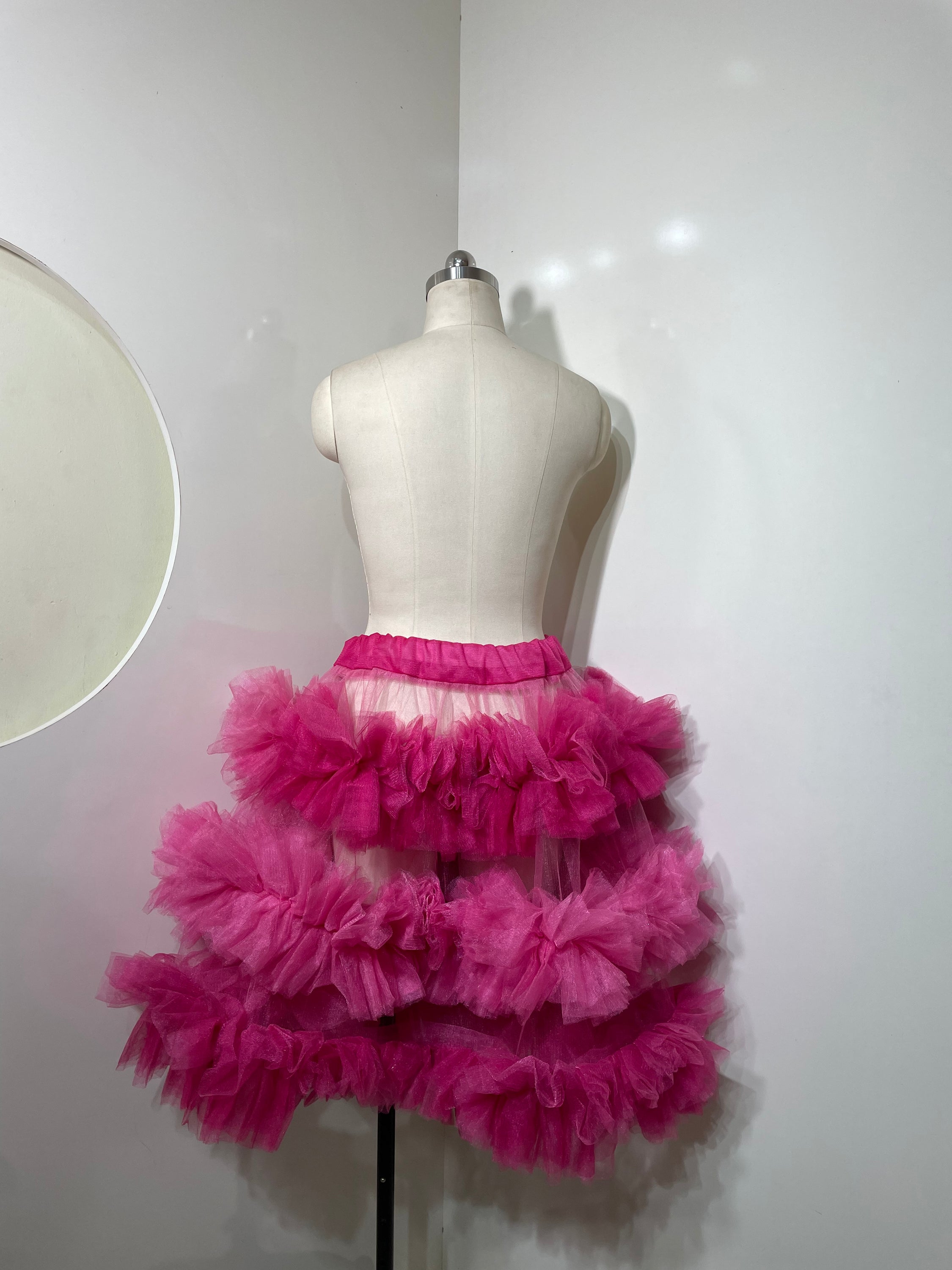 A vibrant pink tiered skirt with ruffle detailing, showcasing a playful and elegant silhouette.