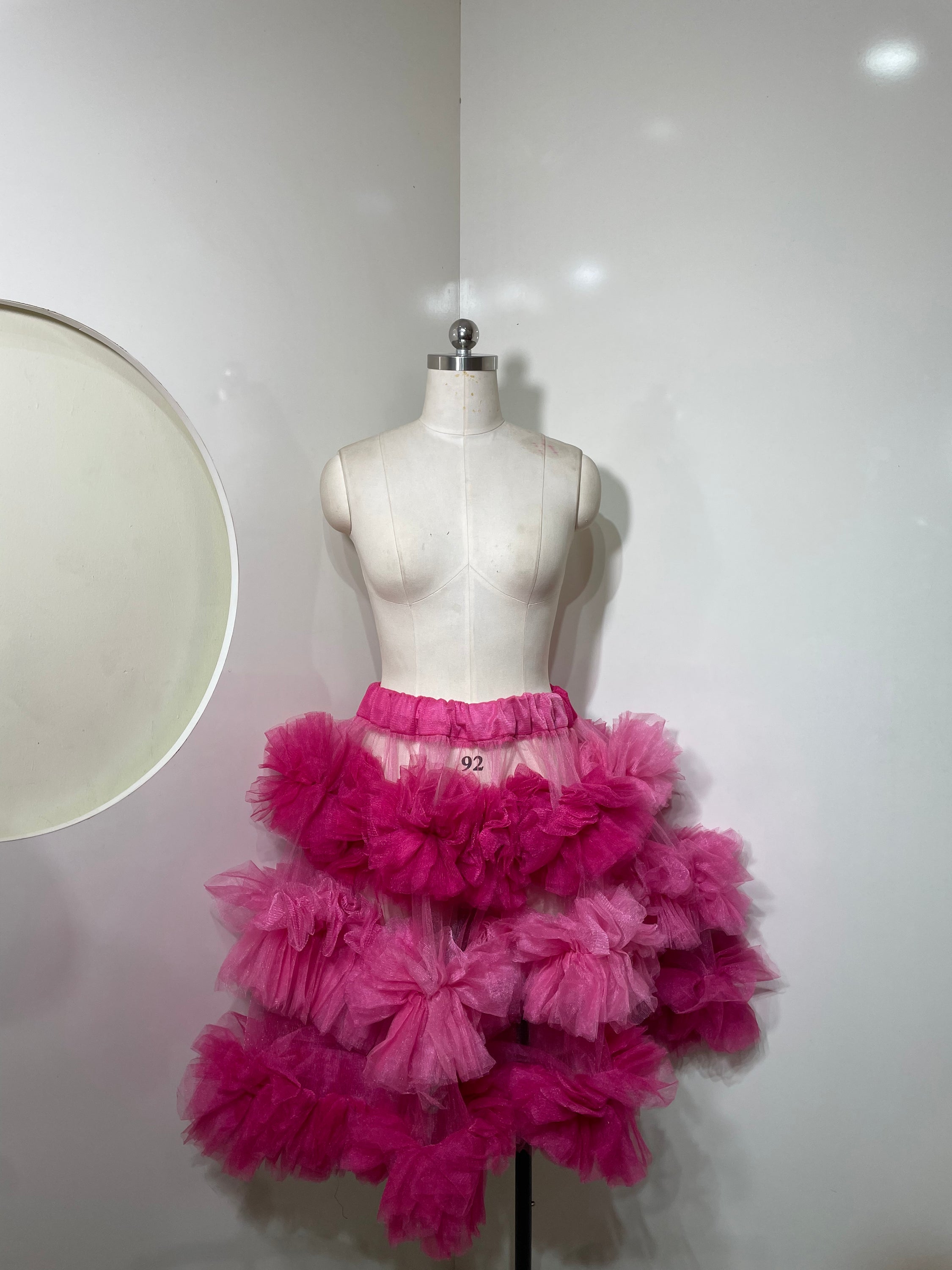 A vibrant pink tiered skirt with ruffle detailing, showcasing a playful and elegant silhouette.