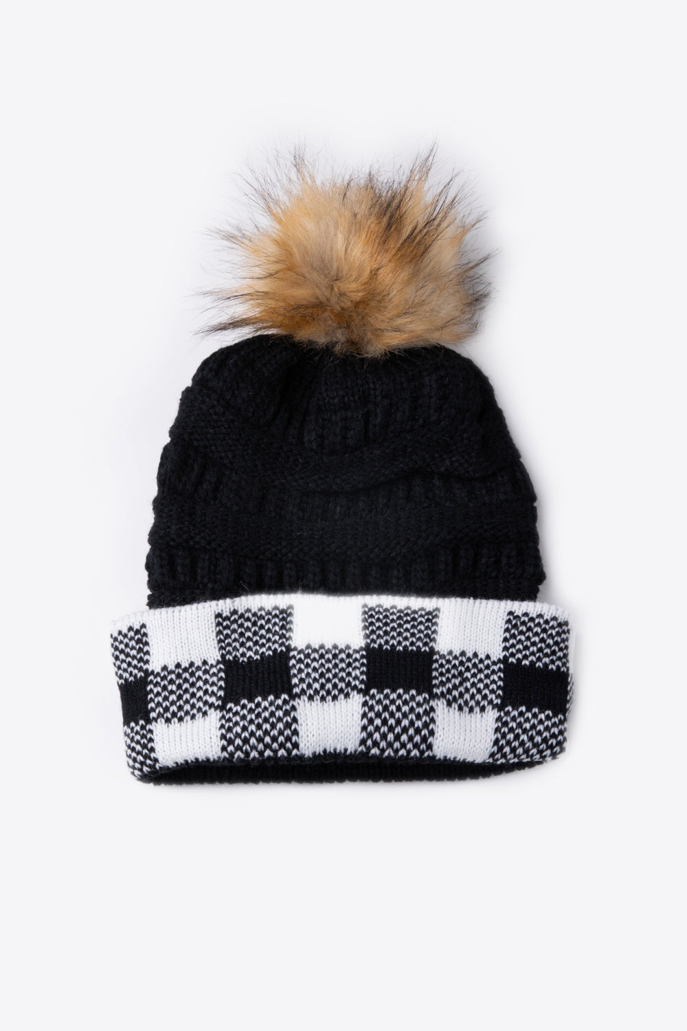 A stylish plaid pom-pom knit beanie in a flat lay style, showcasing its soft acrylic material and trendy design.