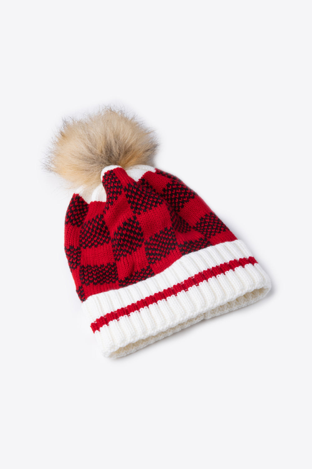 A stylish plaid pom-pom knit beanie in a flat lay style, showcasing its soft acrylic material and trendy design.