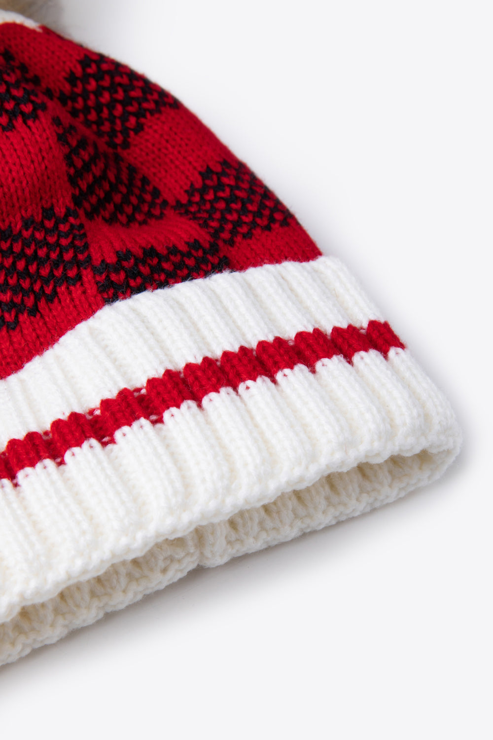 A stylish plaid pom-pom knit beanie in a flat lay style, showcasing its soft acrylic material and trendy design.