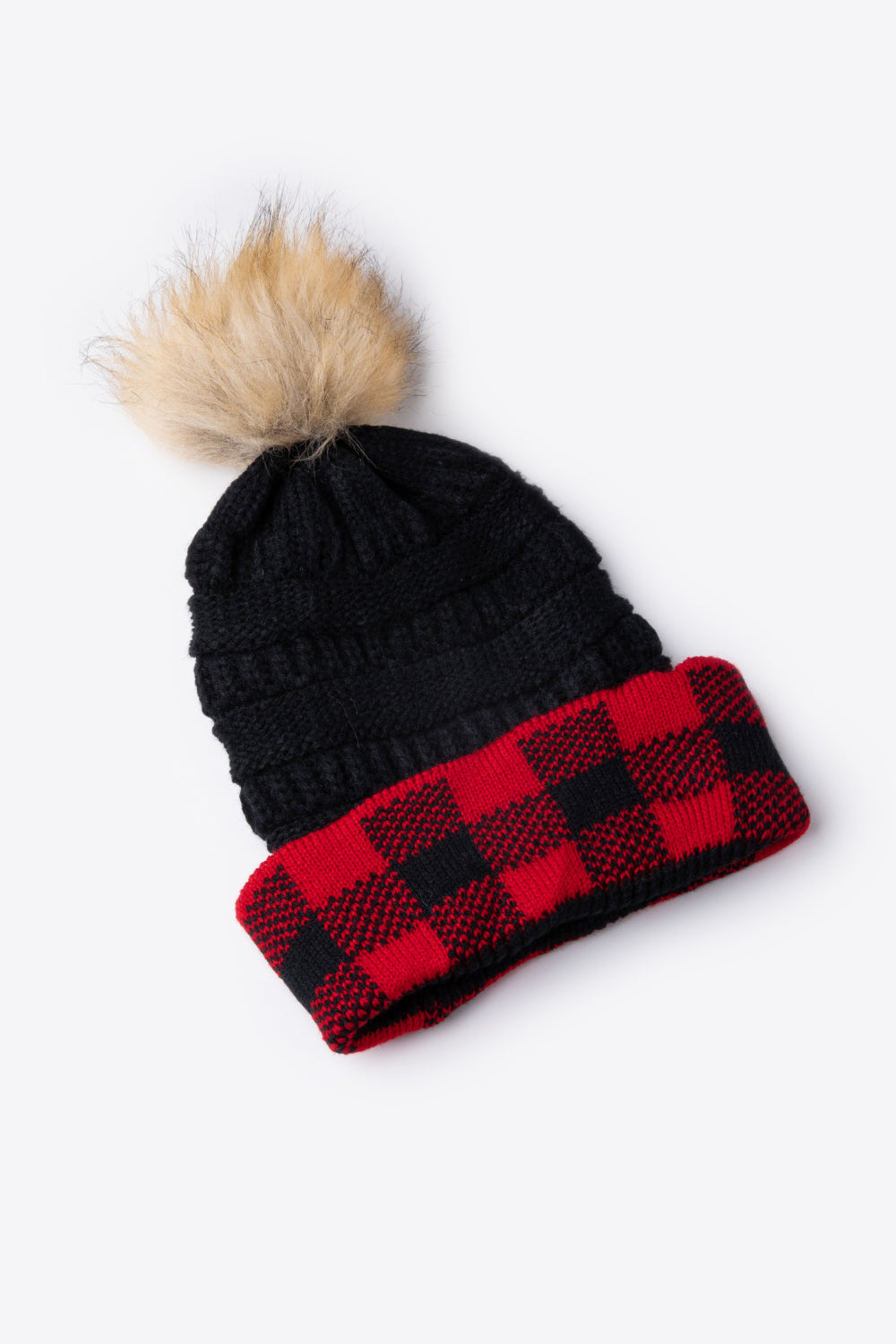 A stylish plaid pom-pom knit beanie in a flat lay style, showcasing its soft acrylic material and trendy design.