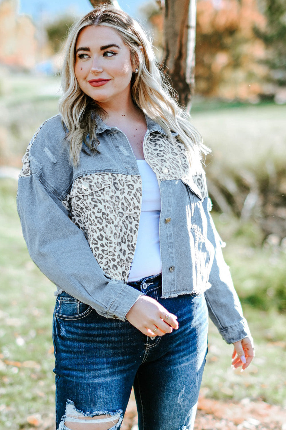 Plus size denim jacket featuring leopard print, distressed details, and raw hem, perfect for casual outdoor wear.