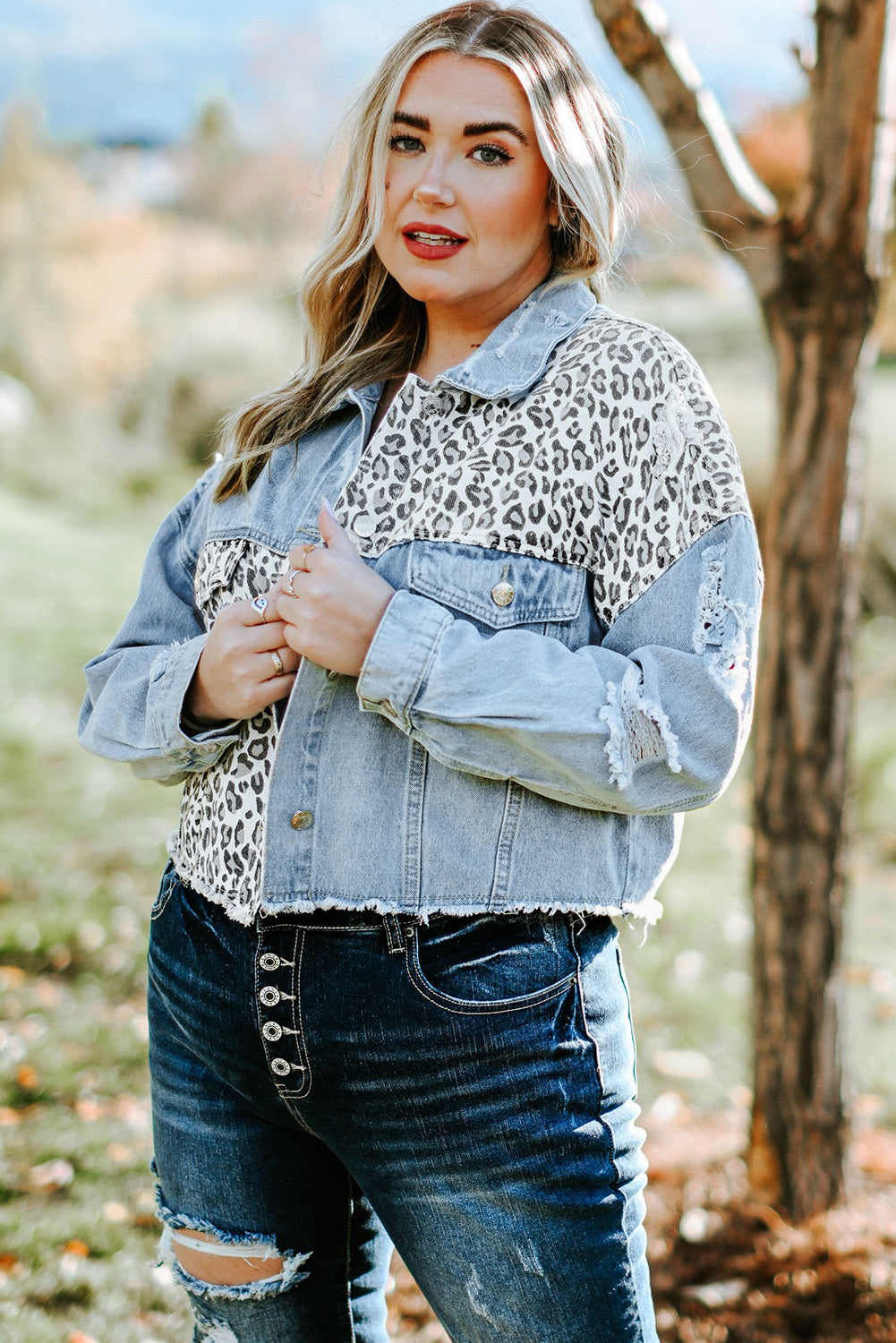 Plus size denim jacket featuring leopard print, distressed details, and raw hem, perfect for casual outdoor wear.