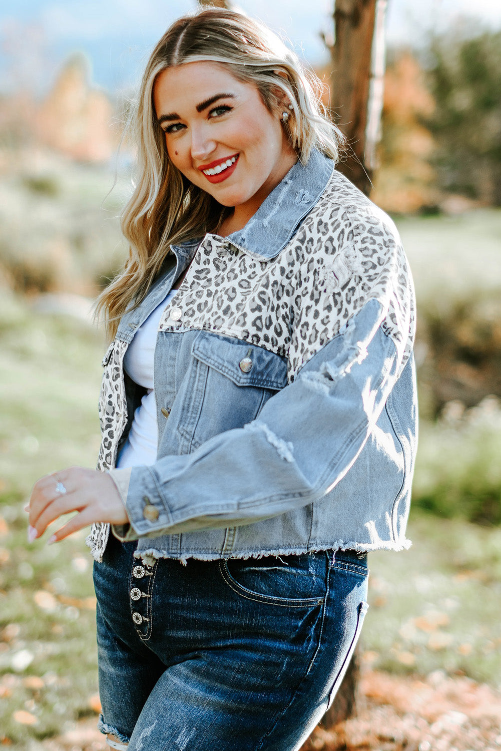 Plus size denim jacket featuring leopard print, distressed details, and raw hem, perfect for casual outdoor wear.