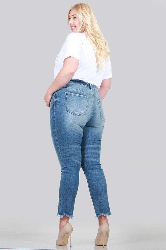 A pair of plus size relaxed skinny jeans featuring a high rise, zipper fly, ankle length with raw cut hem, and five pocket styling.