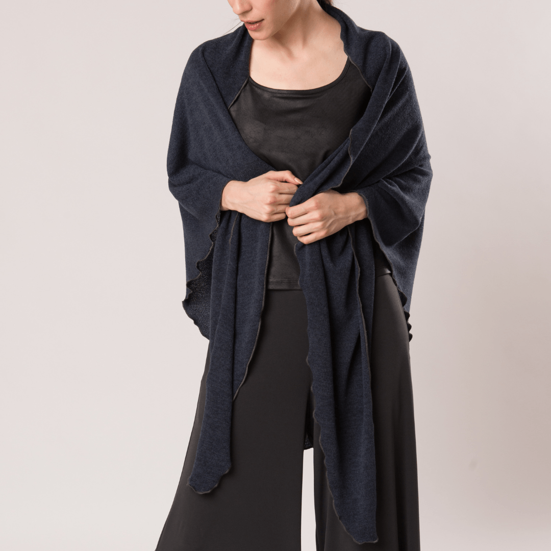 A cozy Mirage Knit pointed shawl draped elegantly, showcasing its soft knit fabric and stylish design.