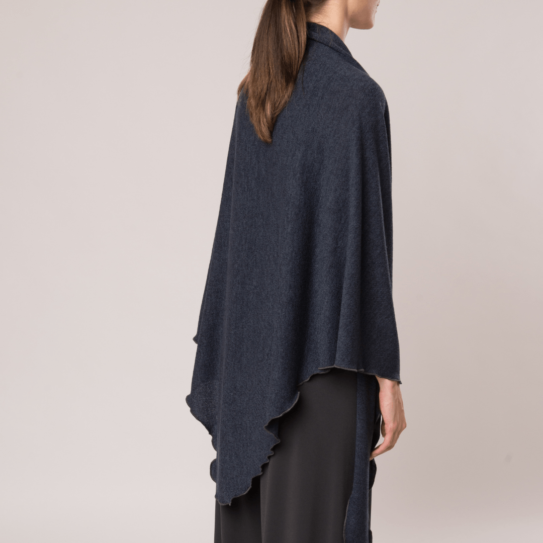 A cozy Mirage Knit pointed shawl draped elegantly, showcasing its soft knit fabric and stylish design.