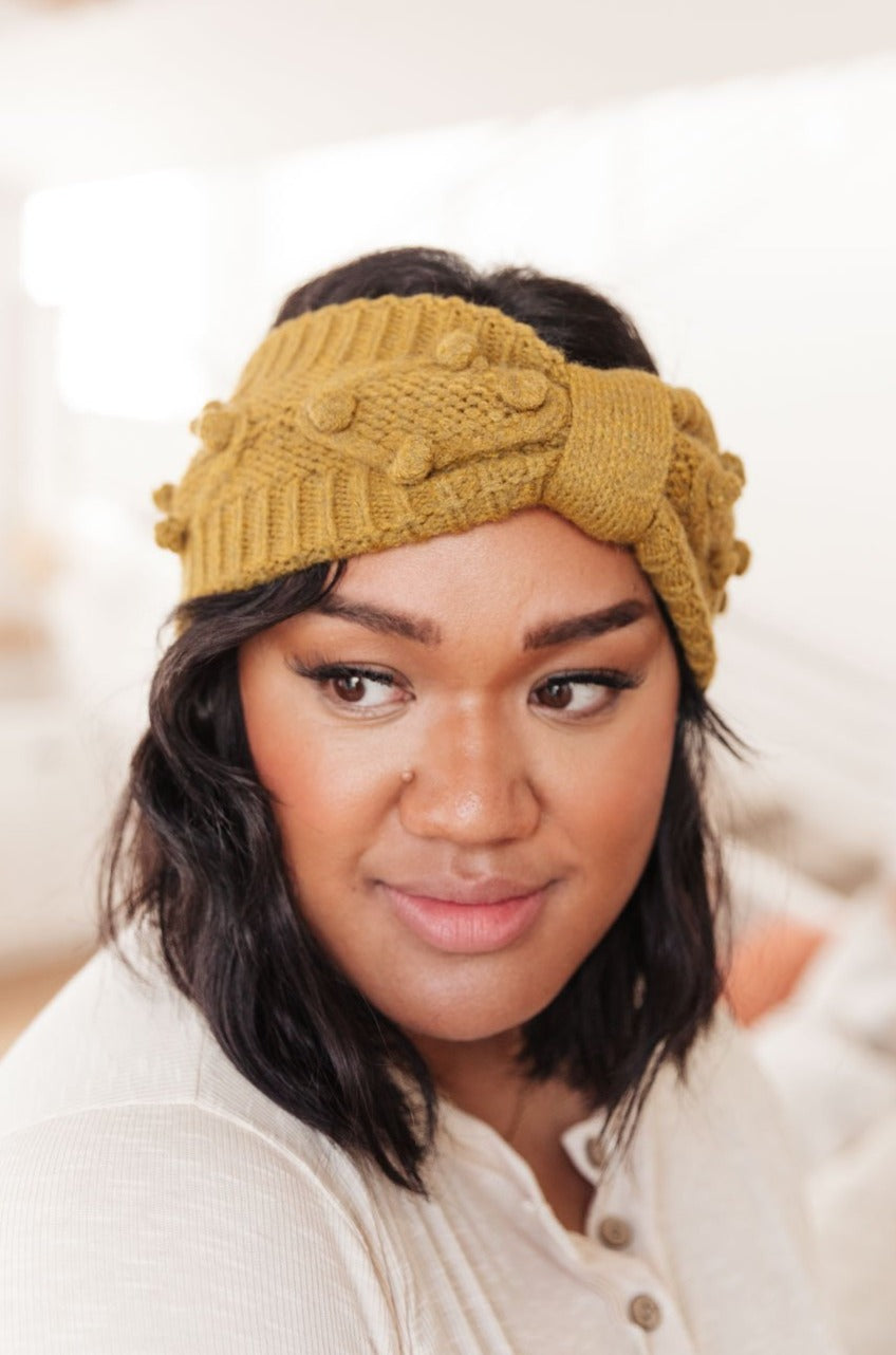 A stylish mustard-colored Pom Knit Head Wrap featuring handmade baubles, perfect for winter wear.