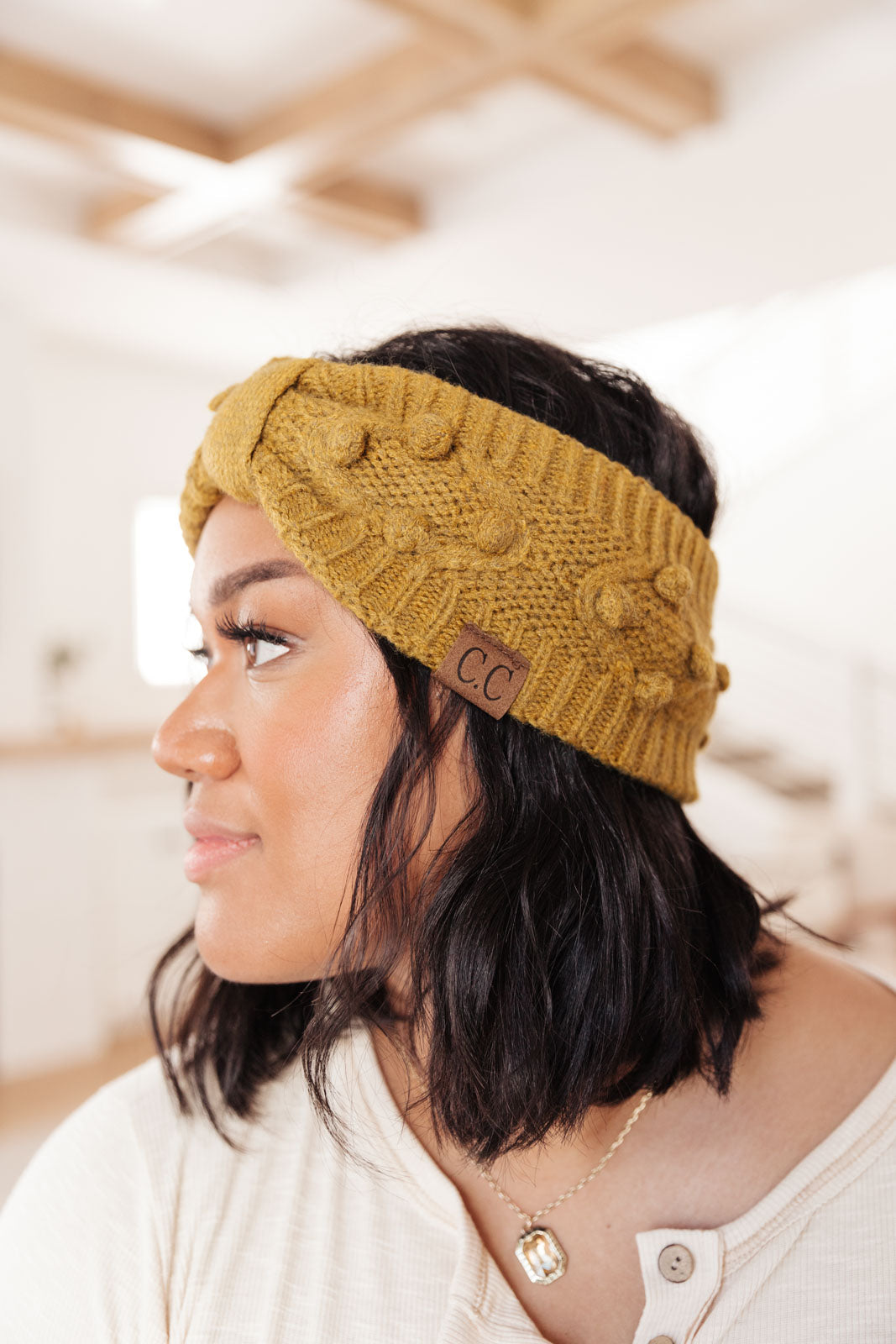 A stylish mustard-colored Pom Knit Head Wrap featuring handmade baubles, perfect for winter wear.