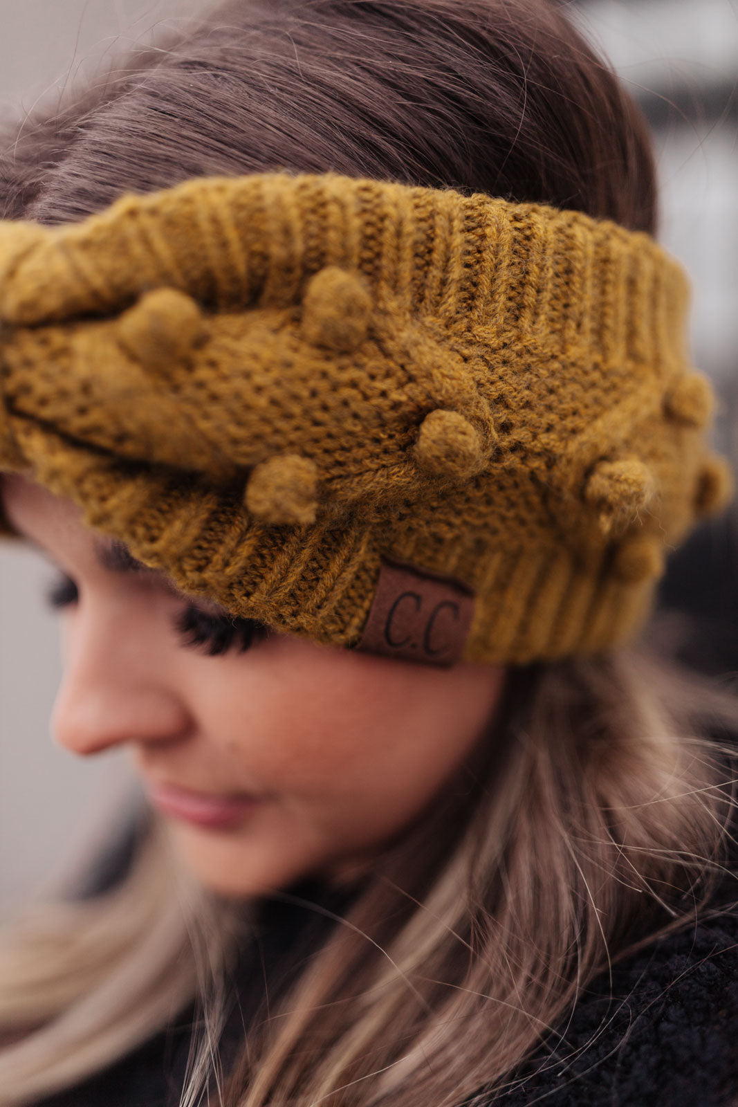 A stylish mustard-colored Pom Knit Head Wrap featuring handmade baubles, perfect for winter wear.