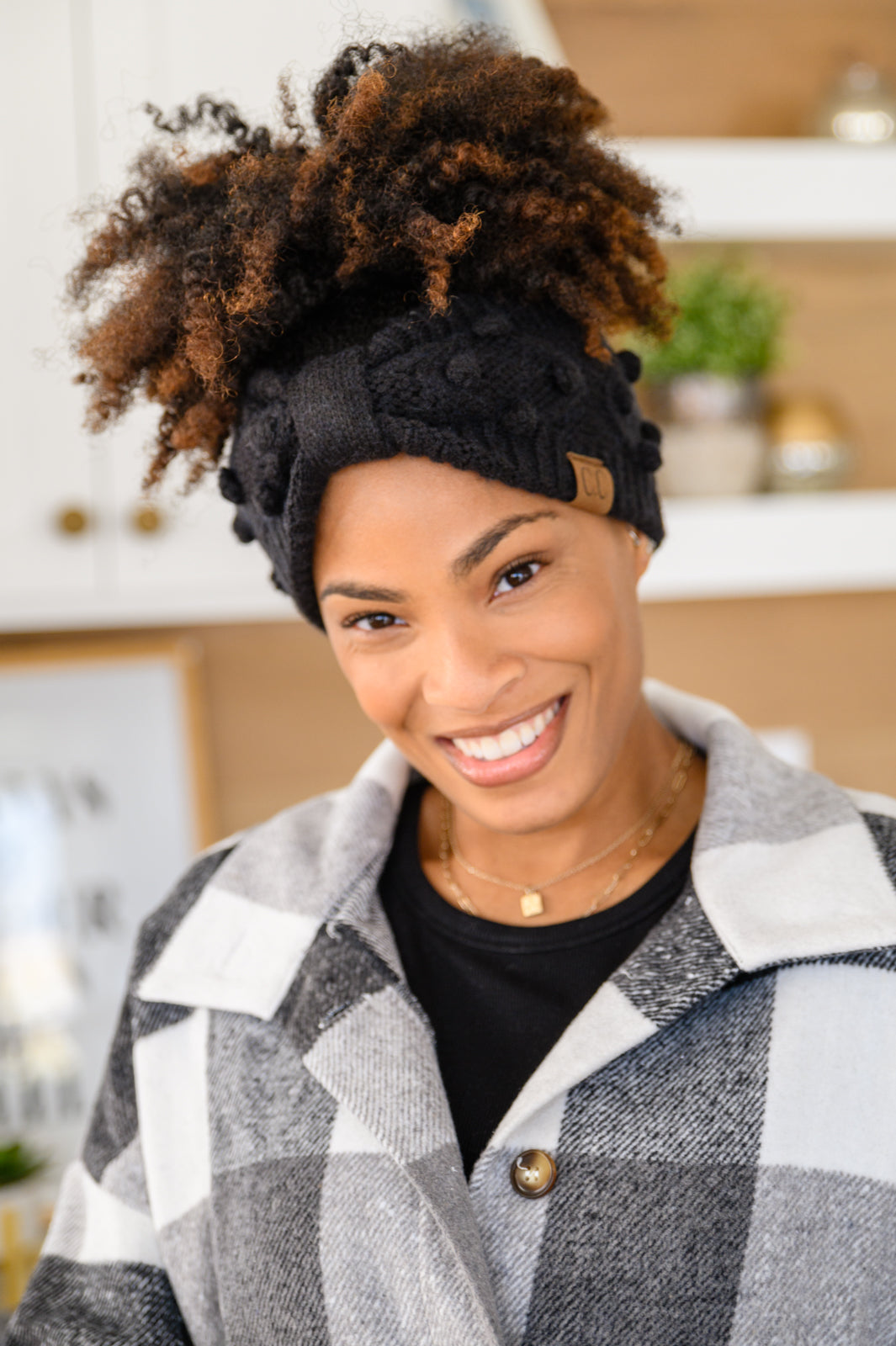 Black Pom Knit Headwrap featuring a bow front and pom pom detailing, made from soft ribbed knit material.