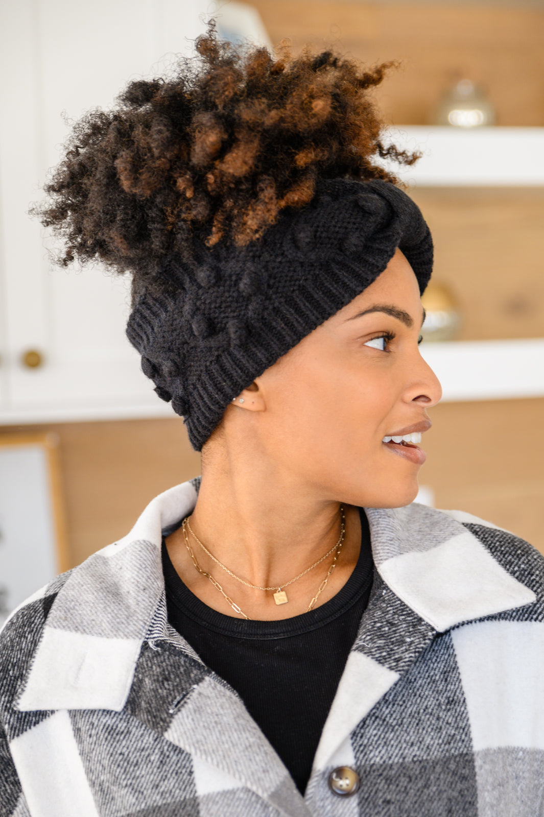 Black Pom Knit Headwrap featuring a bow front and pom pom detailing, made from soft ribbed knit material.