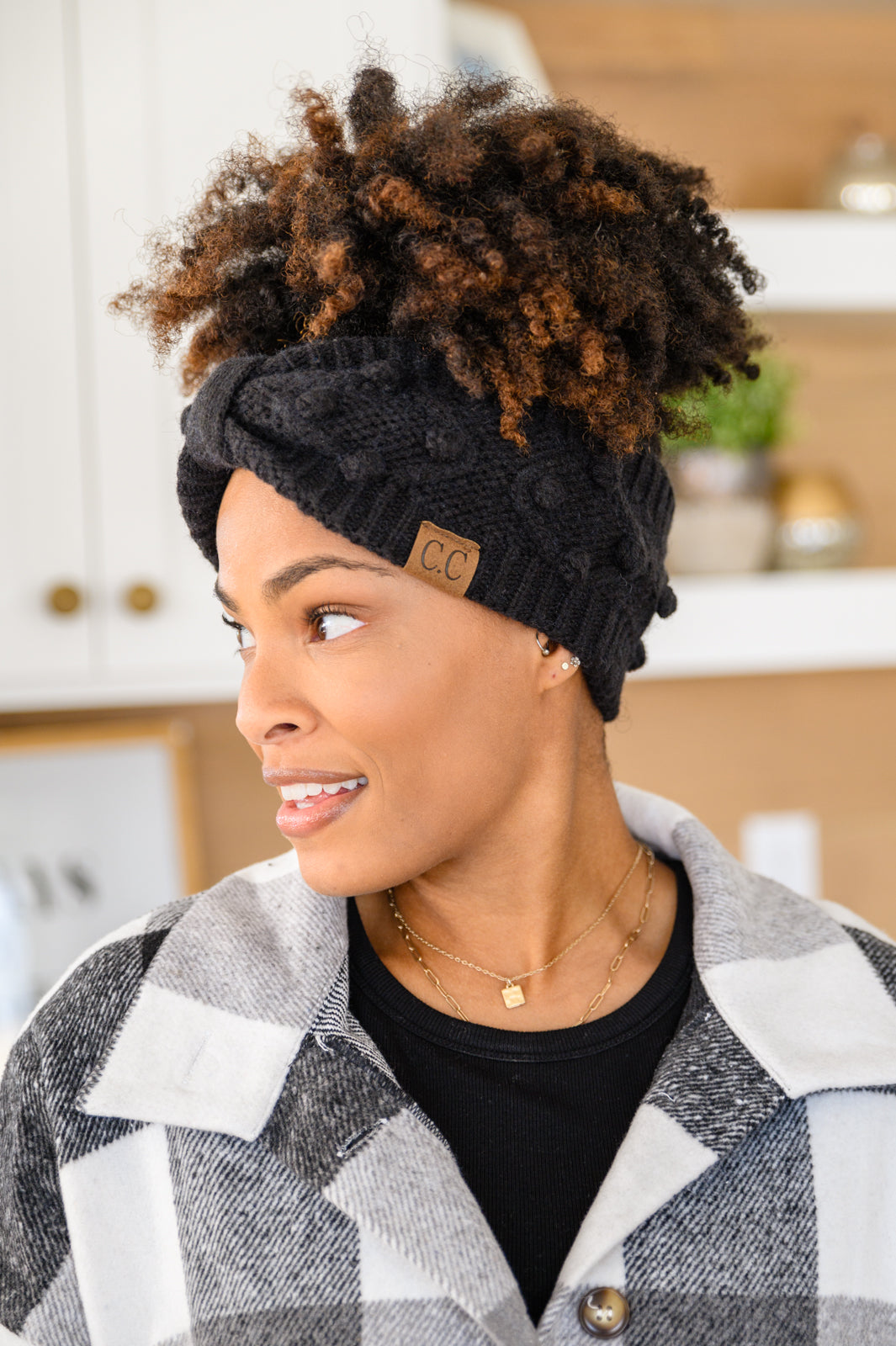 Black Pom Knit Headwrap featuring a bow front and pom pom detailing, made from soft ribbed knit material.